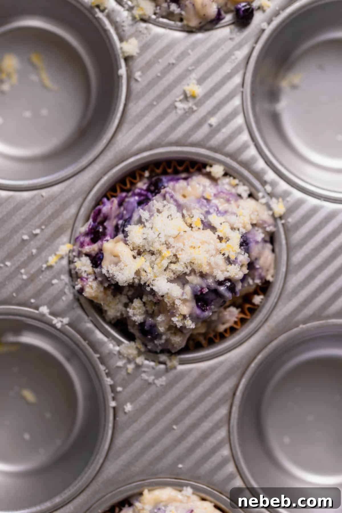 Overhead shot of the muffin batter in the muffin pan, each cup generously filled and topped with sparkling lemon sugar.