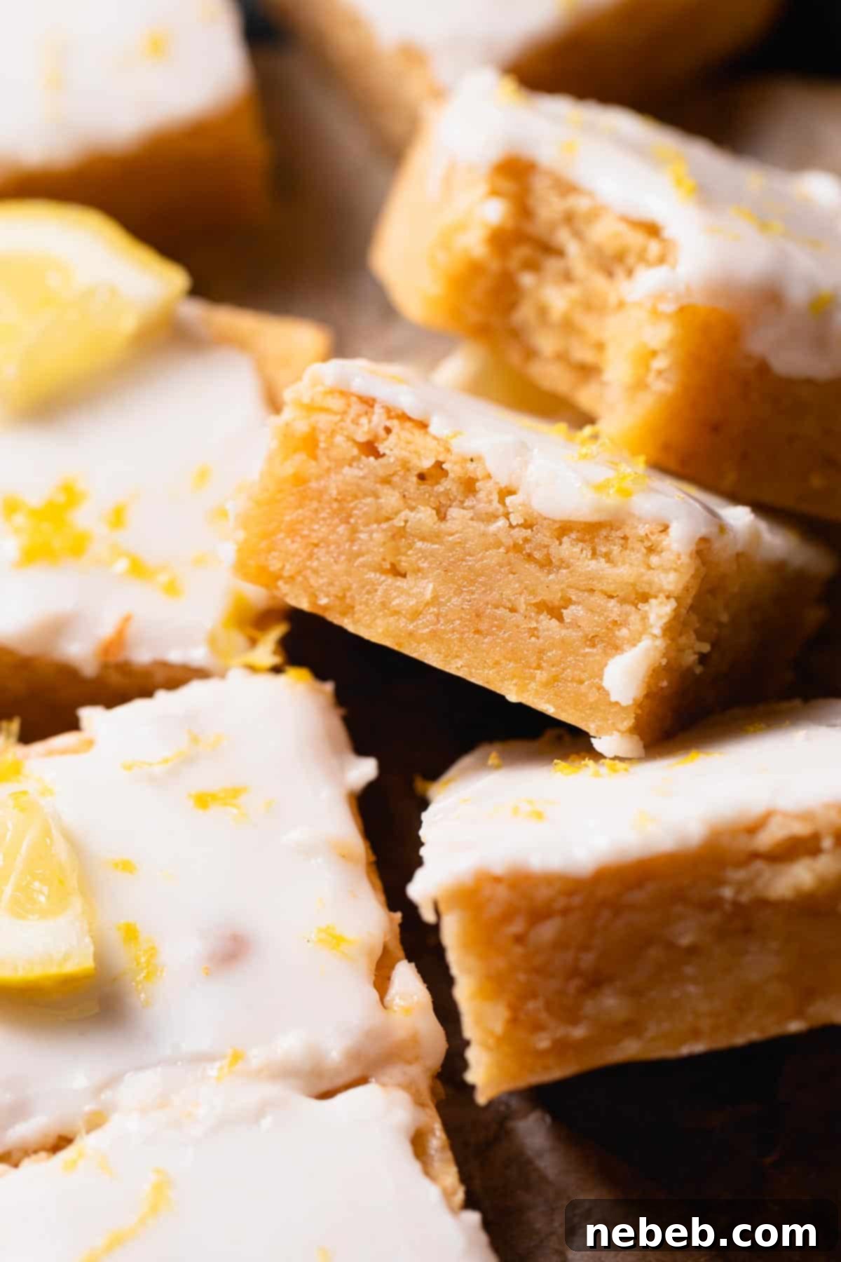 Fudgy lemon brownies with lemon glaze and fresh lemon zest on top, showcasing their irresistible texture.