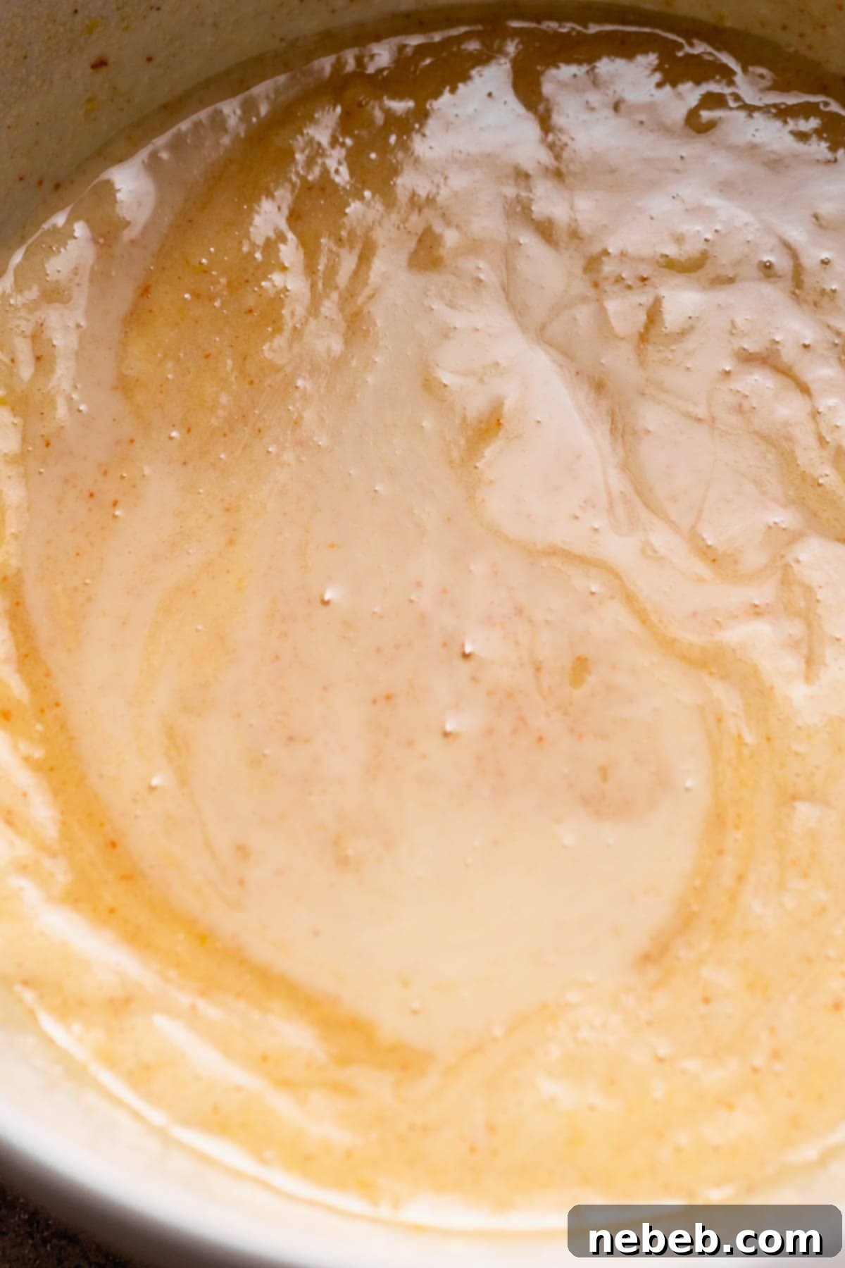 A mixing bowl showing the light and fluffy whisked wet ingredients for the lemon brownie batter.