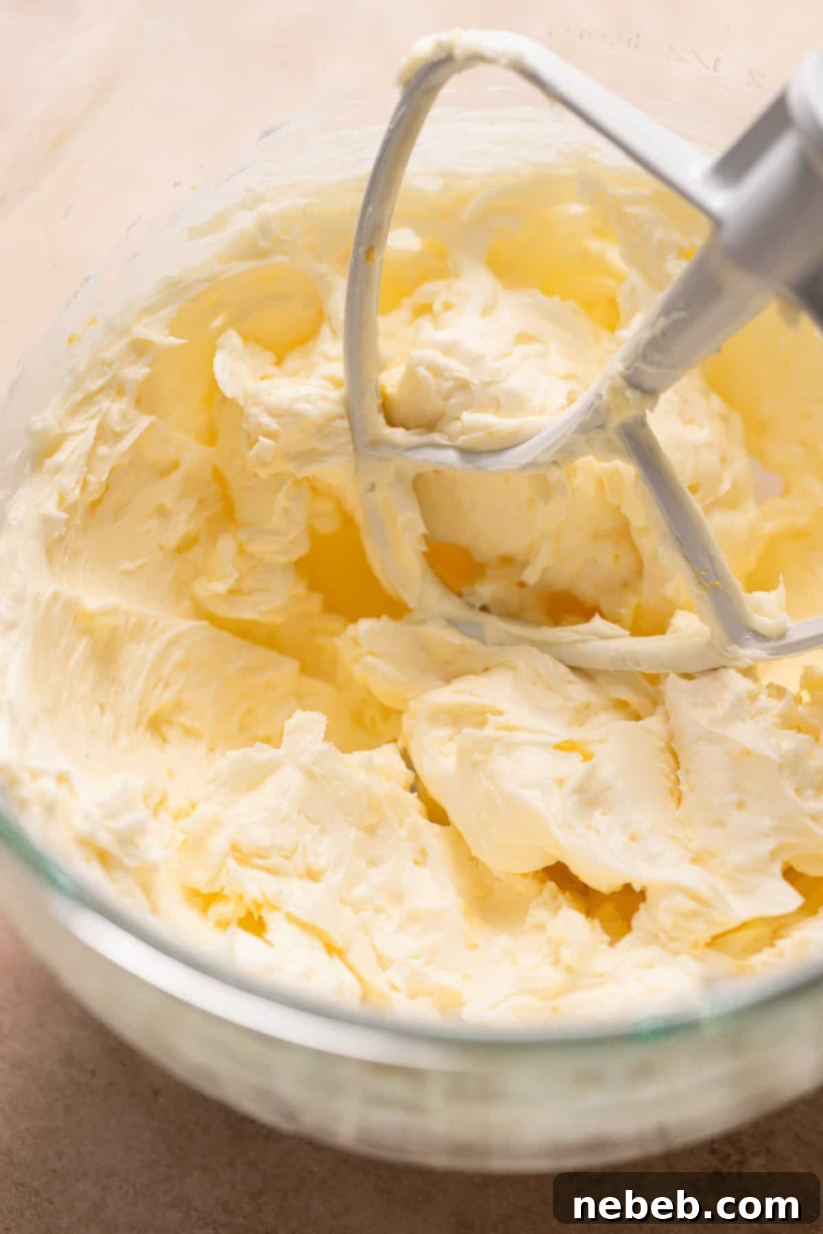 Creamy, pale yellow lemon buttercream frosting in a stand mixer bowl, perfectly whipped.