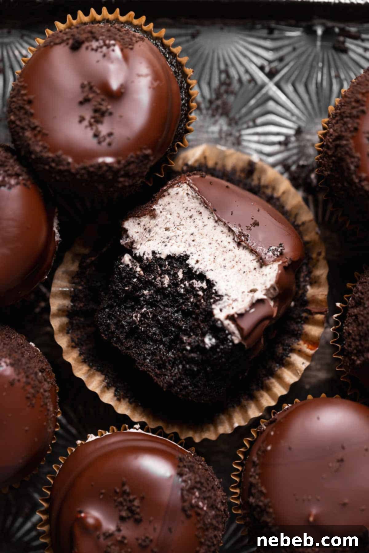 Decadent Chocolate Oreo Cupcakes with a Hi-Hat topping, one with a bite missing, arranged on a baking tray.