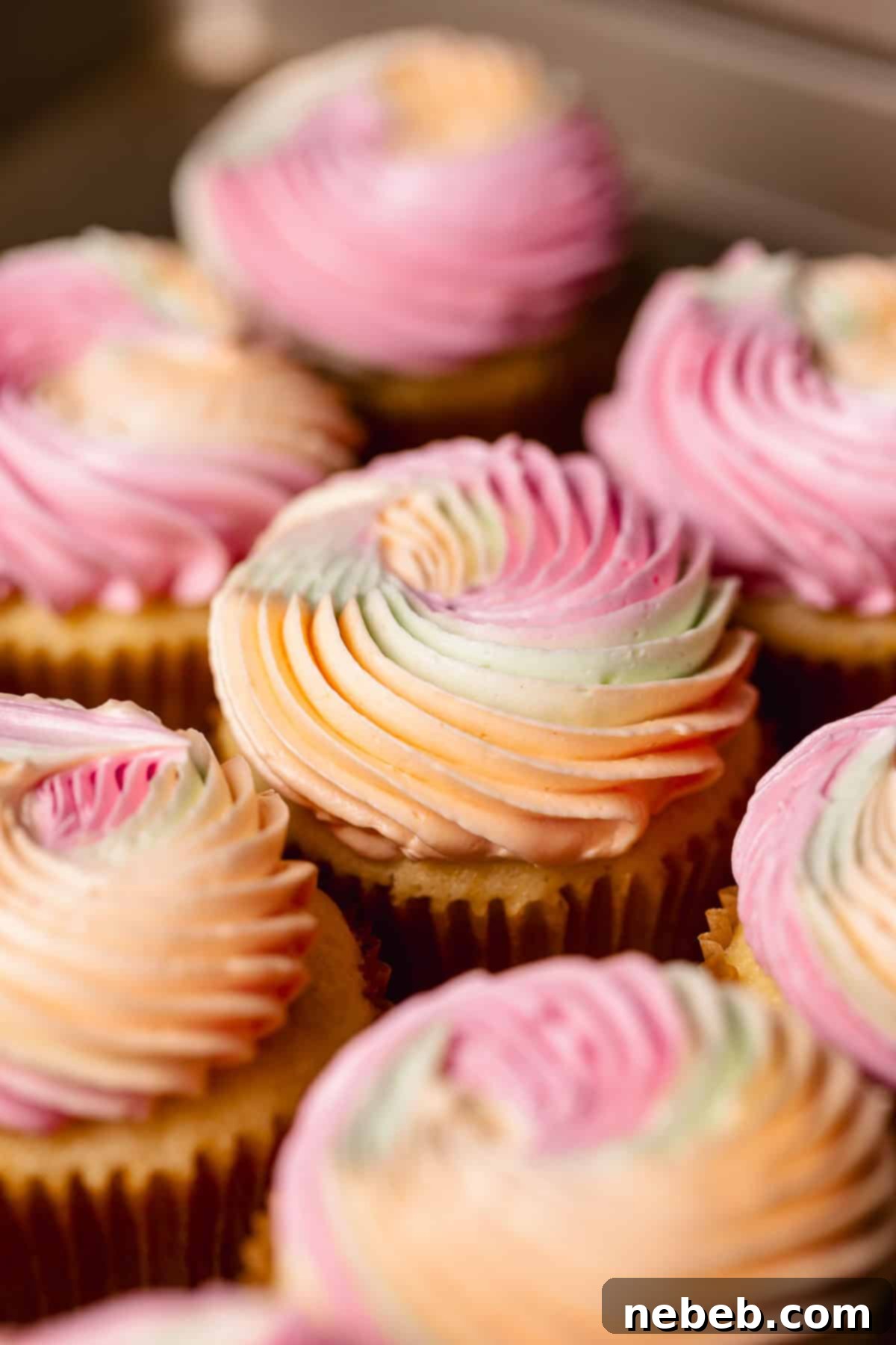 Cupcakes on a baking sheet after being frosted with the colorful buttercream and adorned with sprinkles.