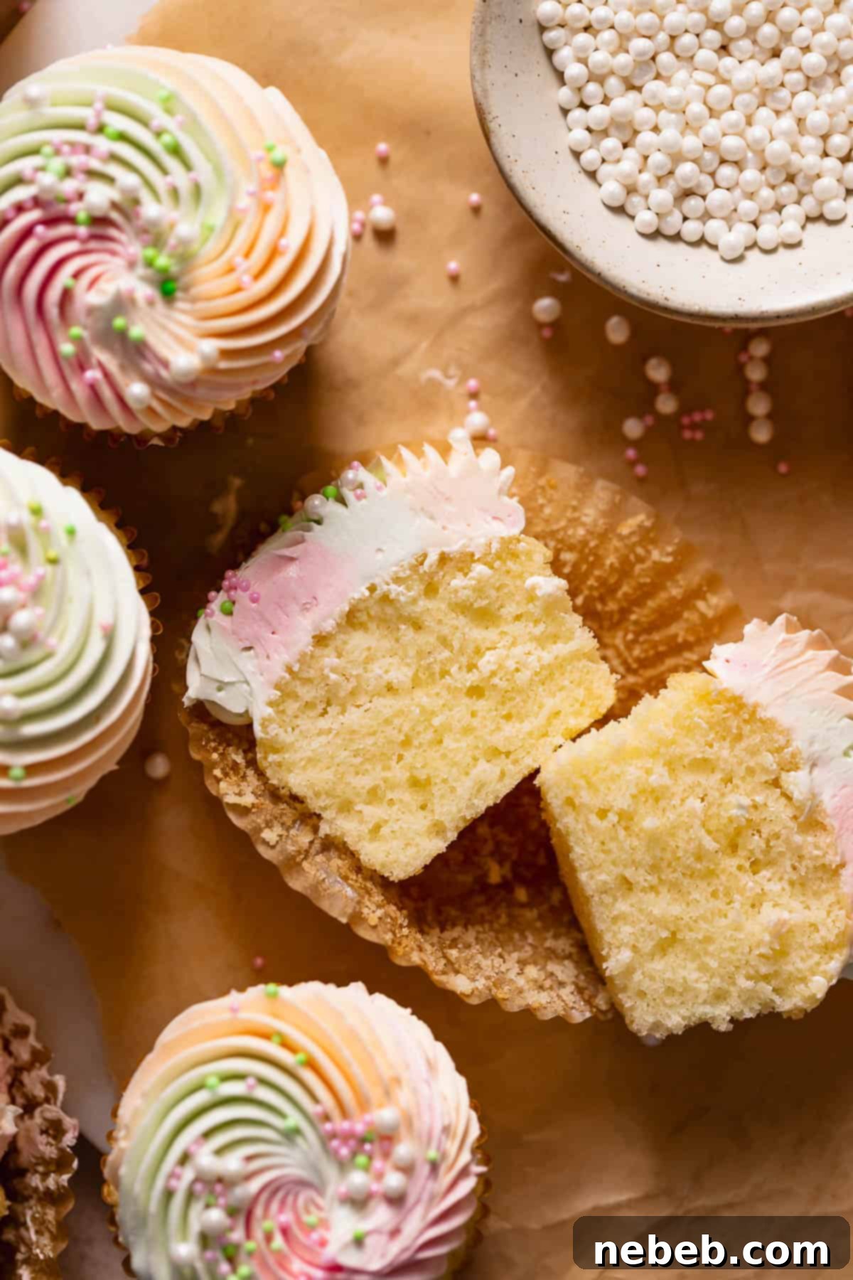 Rainbow sherbet cupcake cut in half to show the tender, colorful texture inside, adorned with sprinkles.