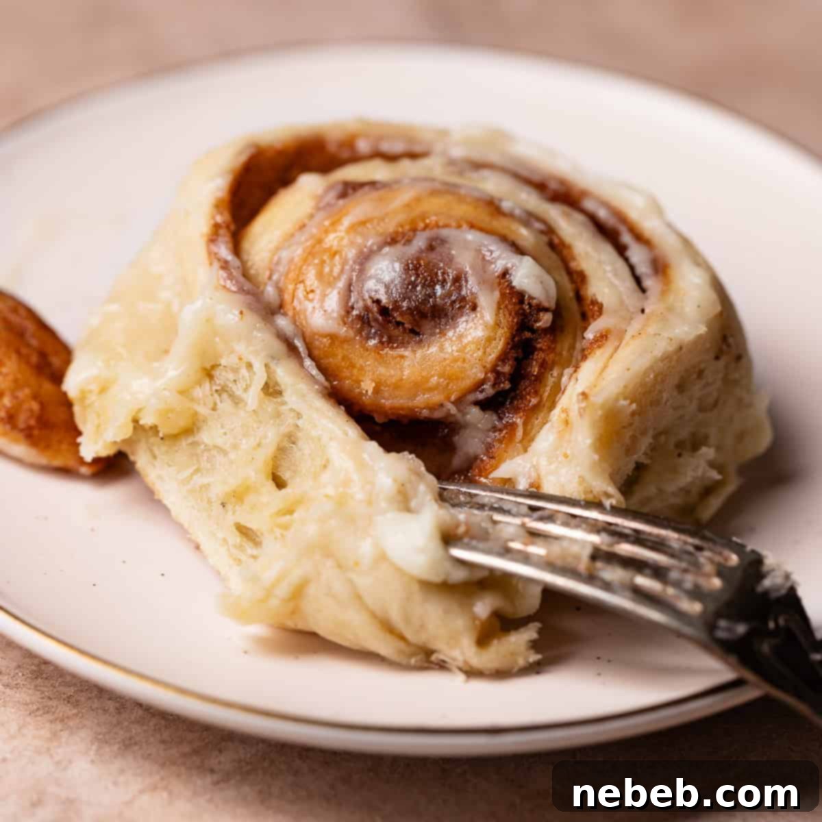 Brown butter rolls on a white plate with a fork digging into it.