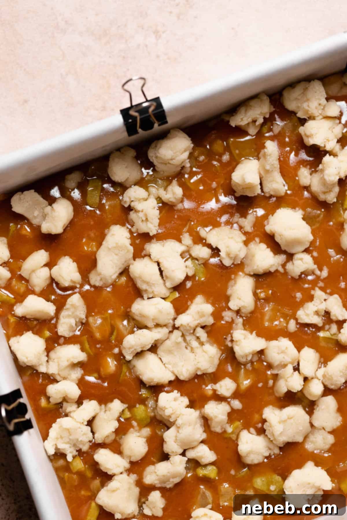 Apple caramel bars sprinkled with reserved shortbread crumbs, ready for the final bake.