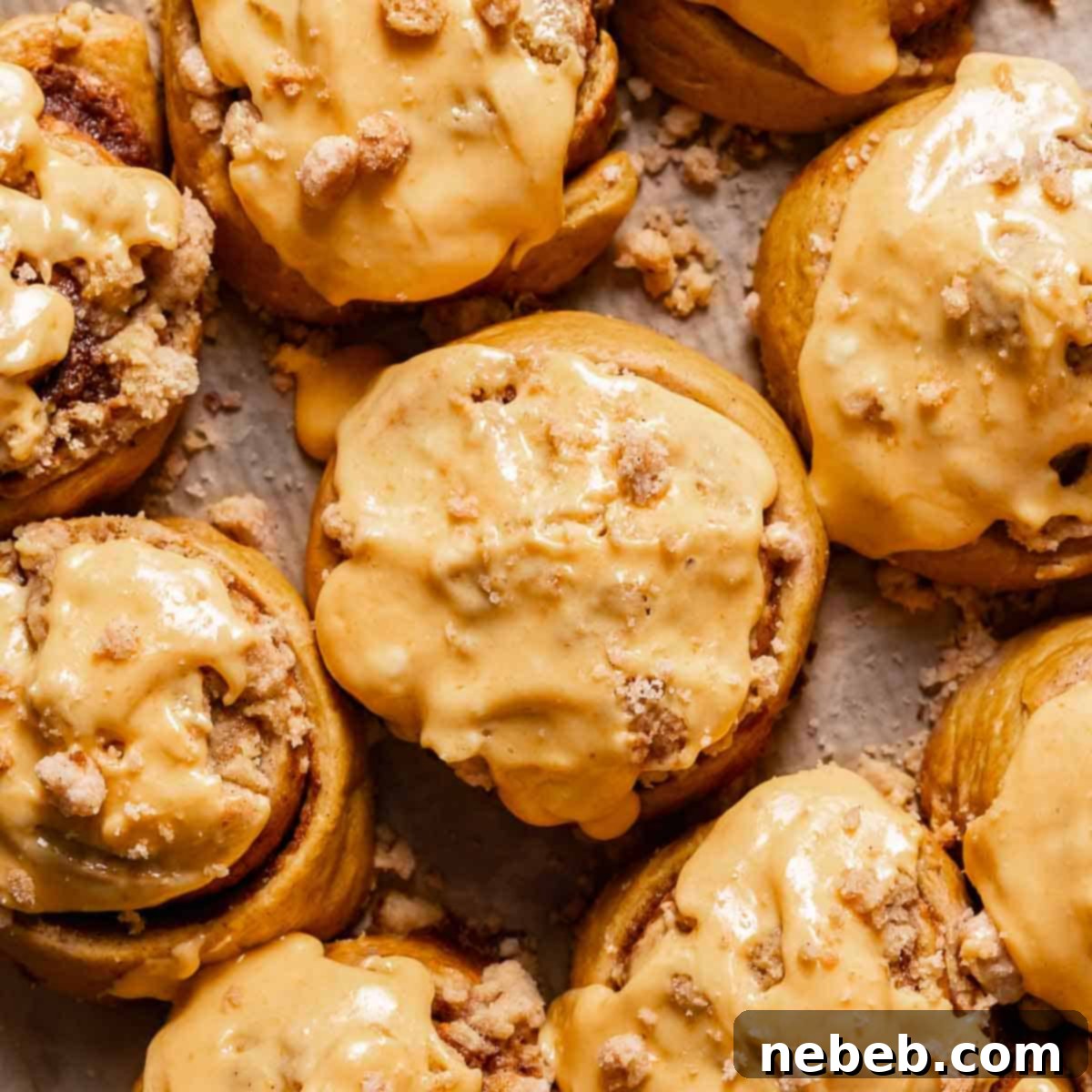 Pumpkin cinnamon rolls with cream cheese icing on a baking sheet.