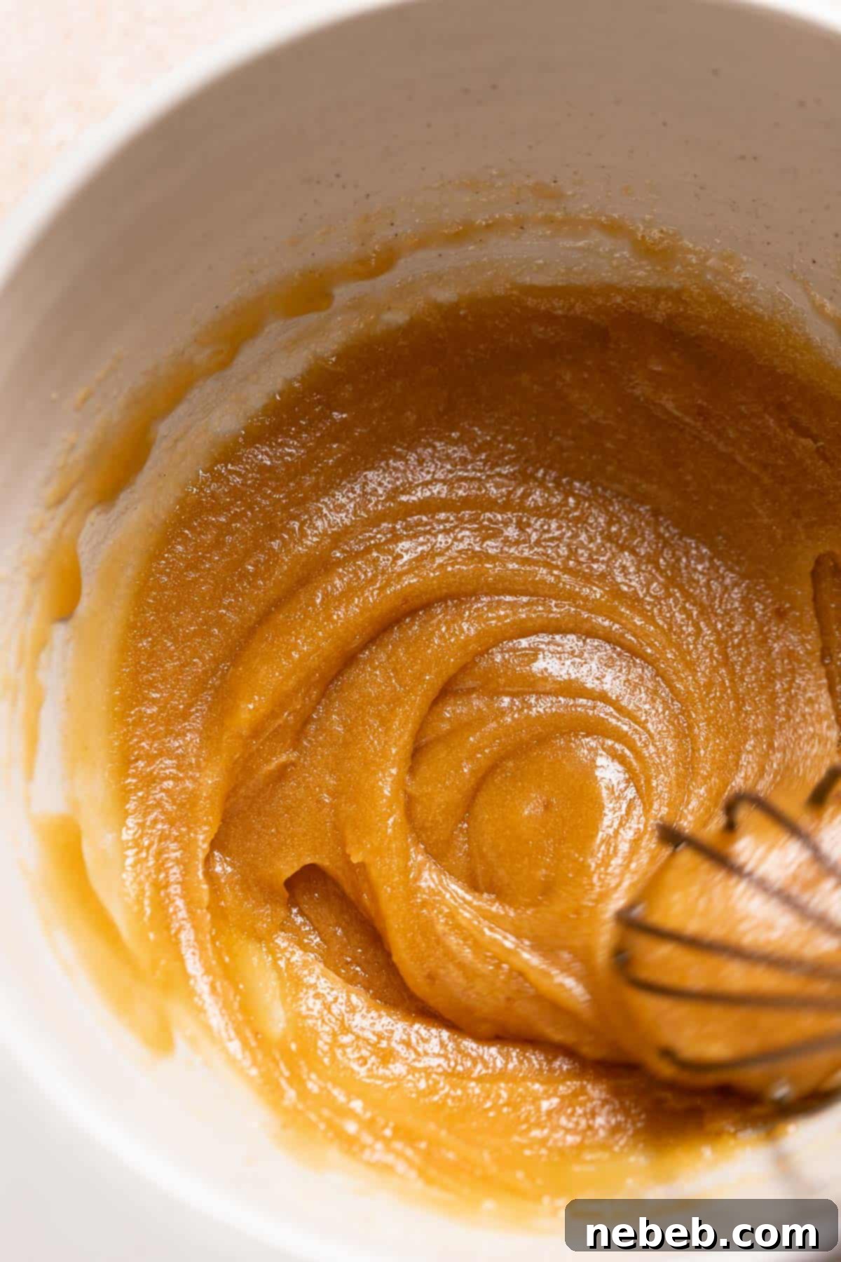 A mixing bowl with the whisked melted butter and sugars, showcasing a smooth, golden mixture.