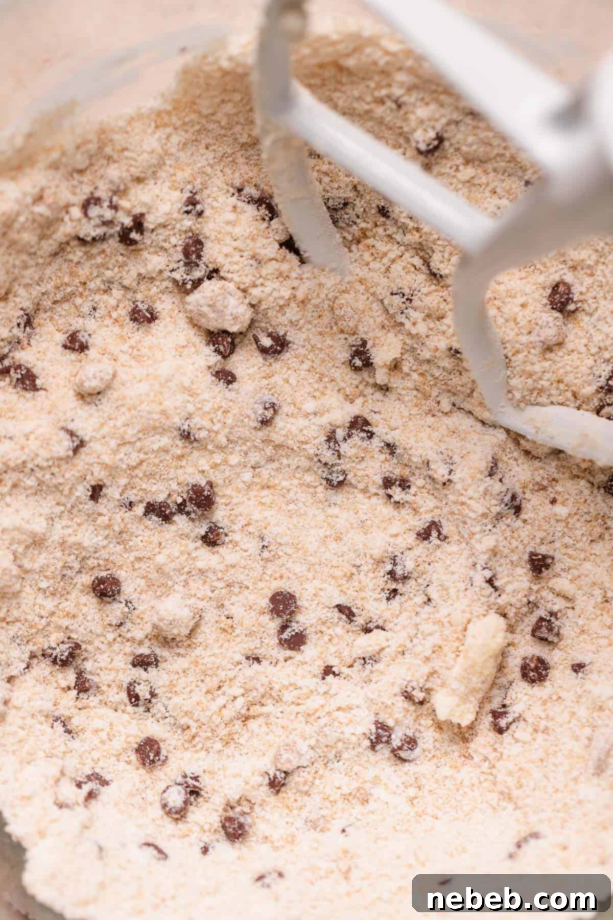 A mixing bowl with the butter and dry ingredients combined, showing a crumbly texture.