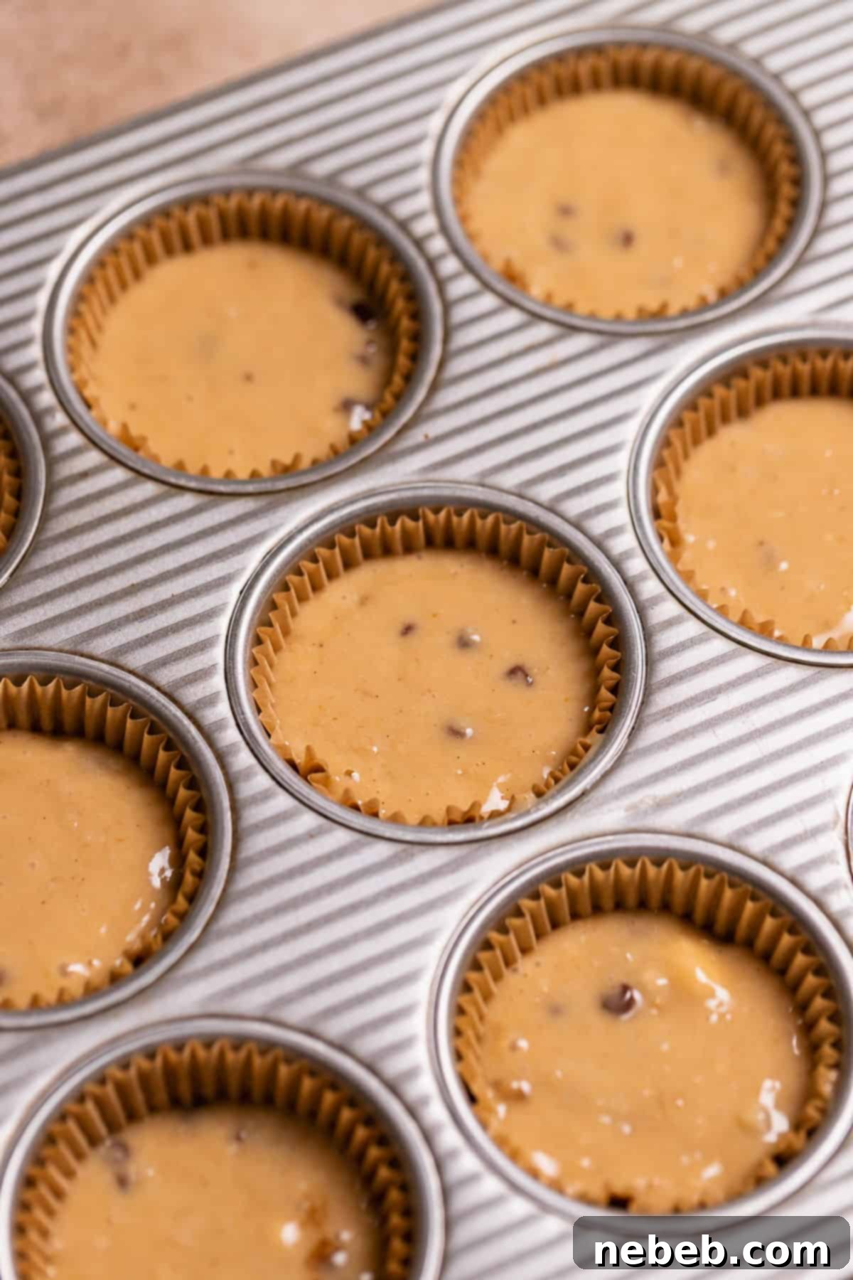 A cupcake pan with liners full of cupcake batter before baking, showing even portions.