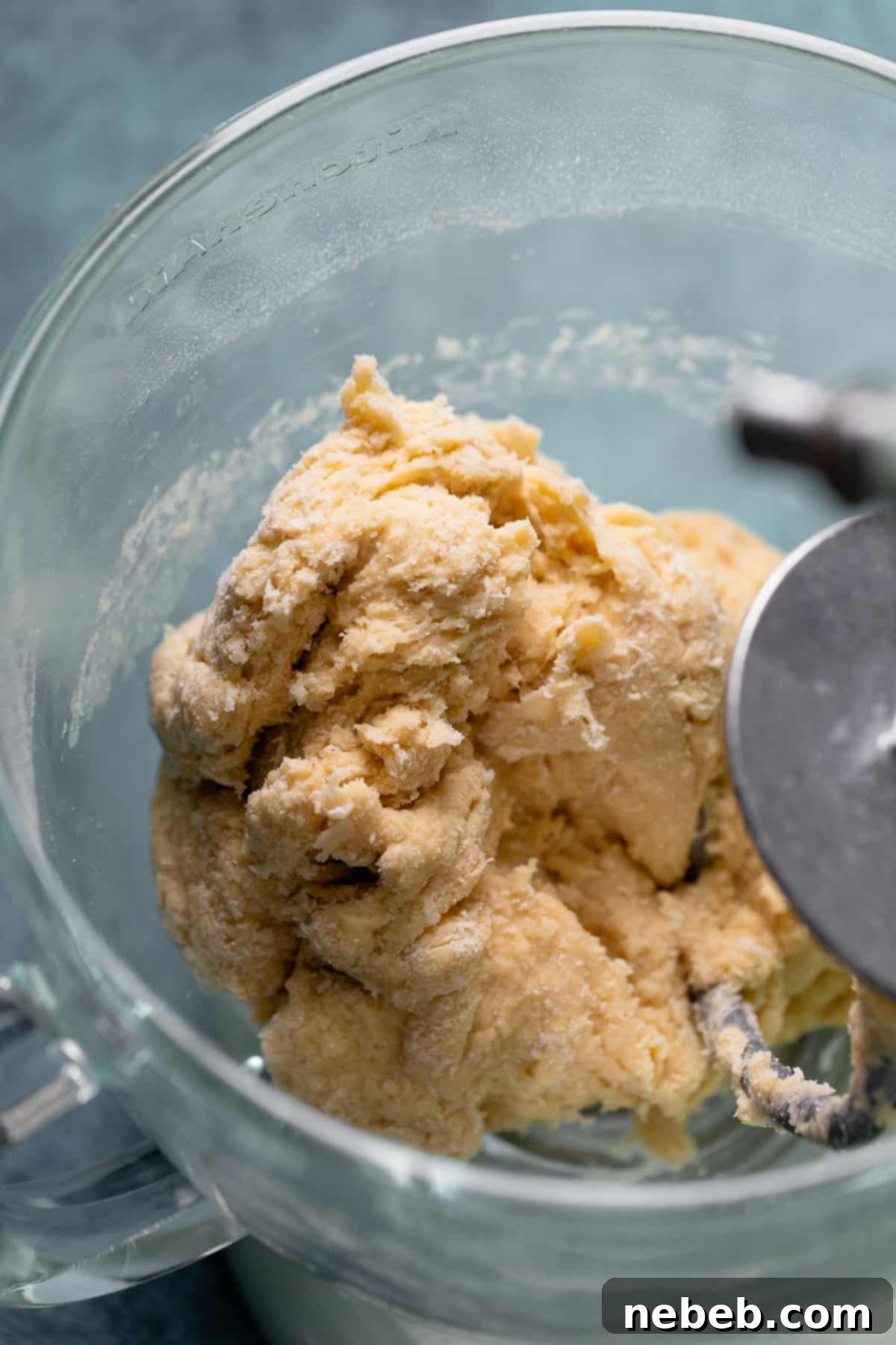 Sweet roll dough in a mixing bowl, looking rough and dry after initial mixing.