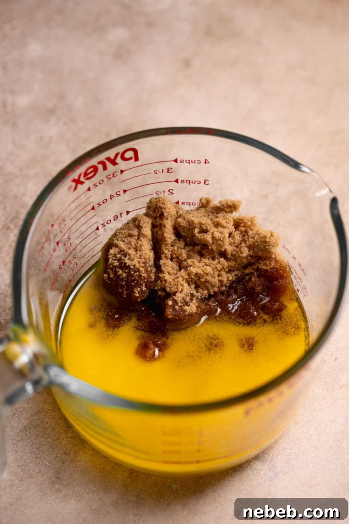 Melted butter and a mixture of granulated and brown sugars in a clear glass bowl, glistening and ready for the next step.