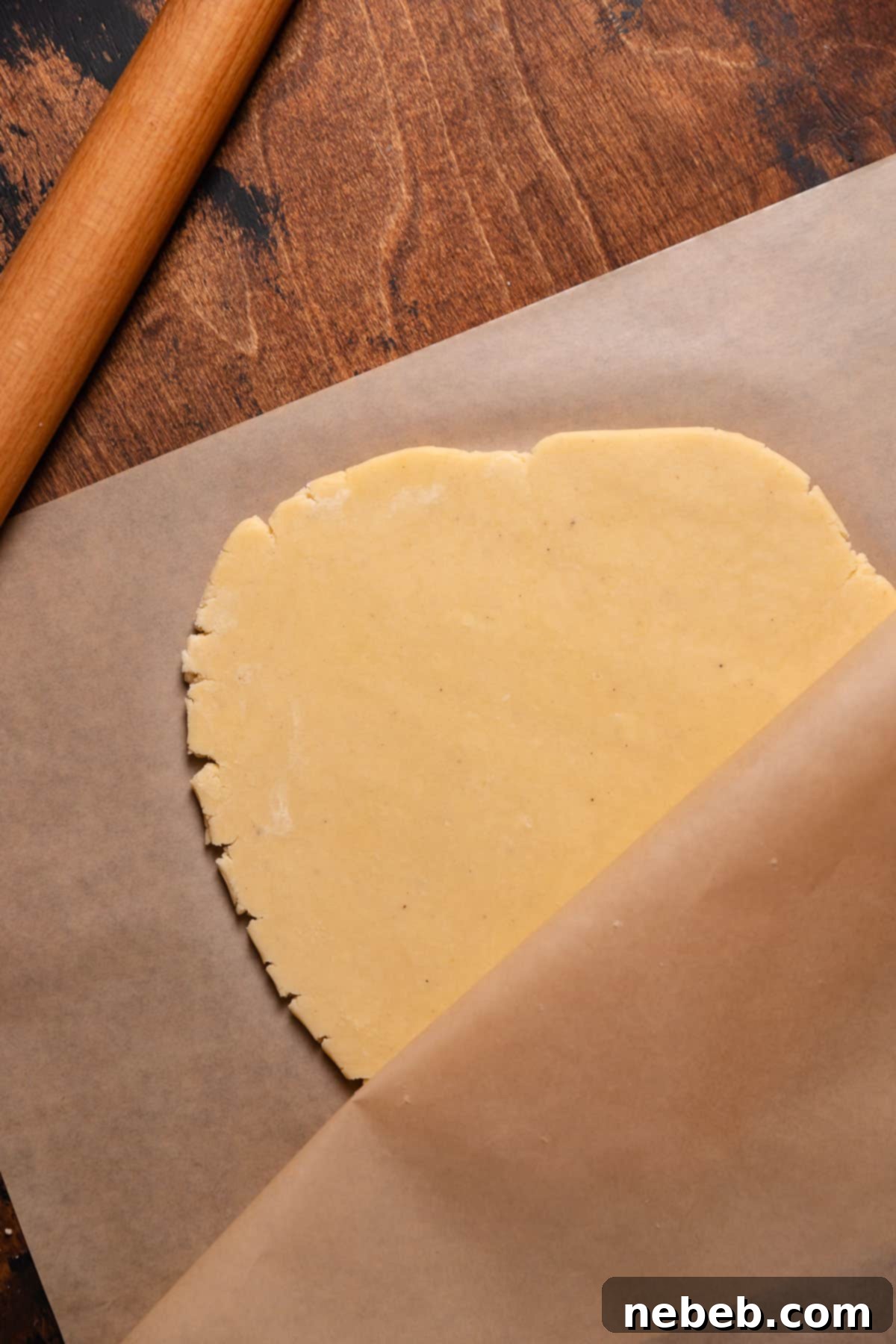 Perfect Bakery-Style Cut-Out Sugar Cookies 7 Sugar cookie dough being rolled between sheets of parchment paper.