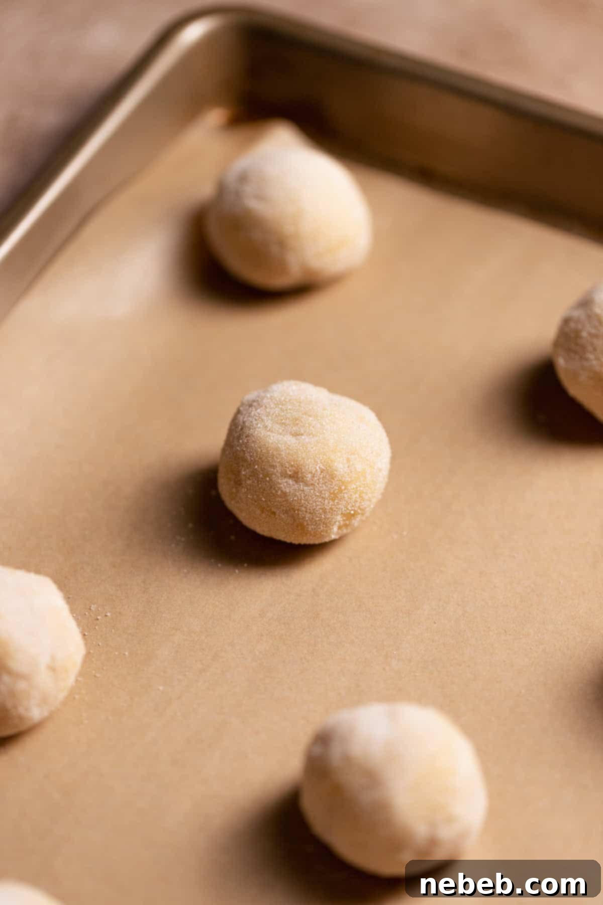 Sugar cookie balls rolled in granulated sugar before baking.