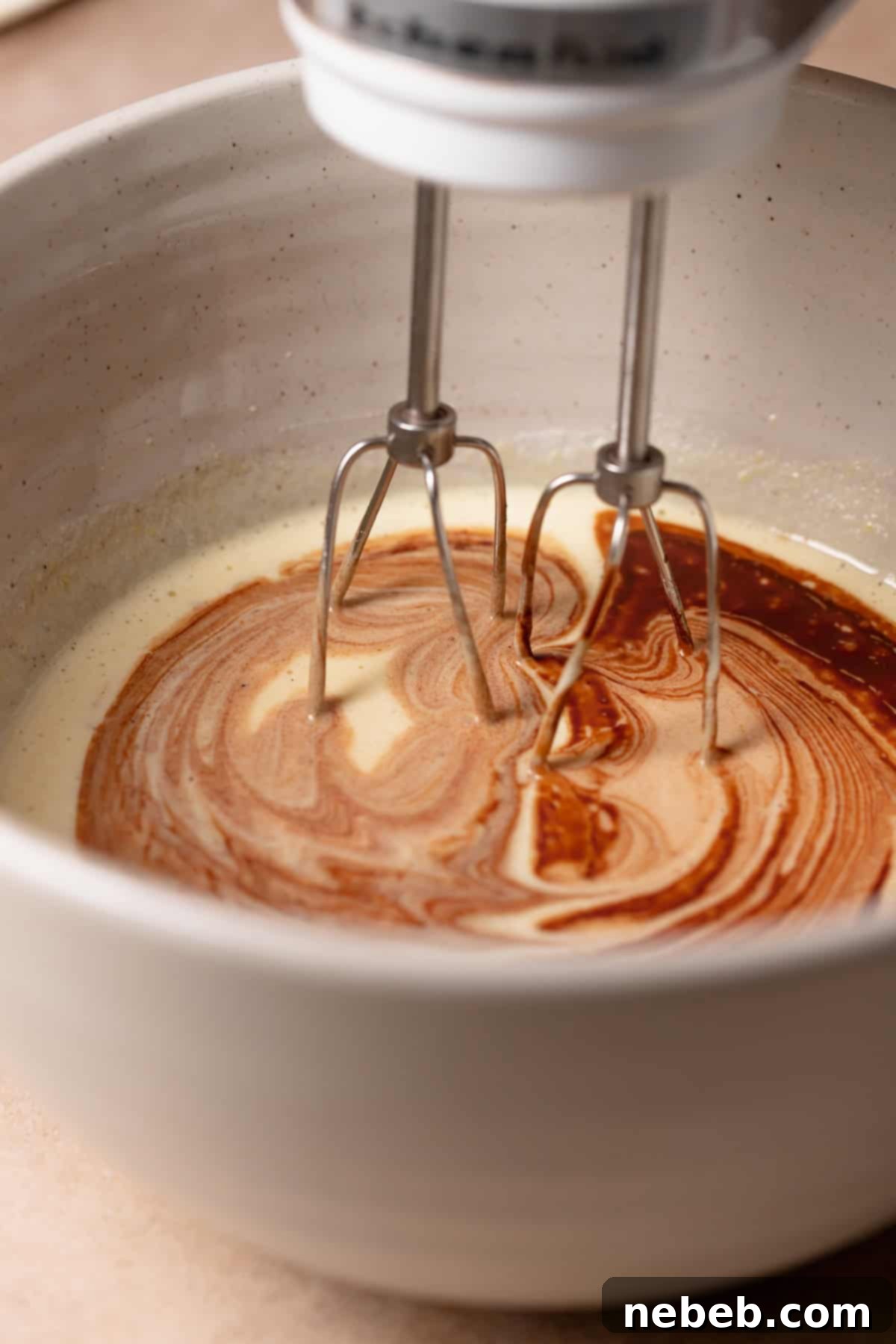 The melted chocolate being mixed into the beaten eggs and sugar.