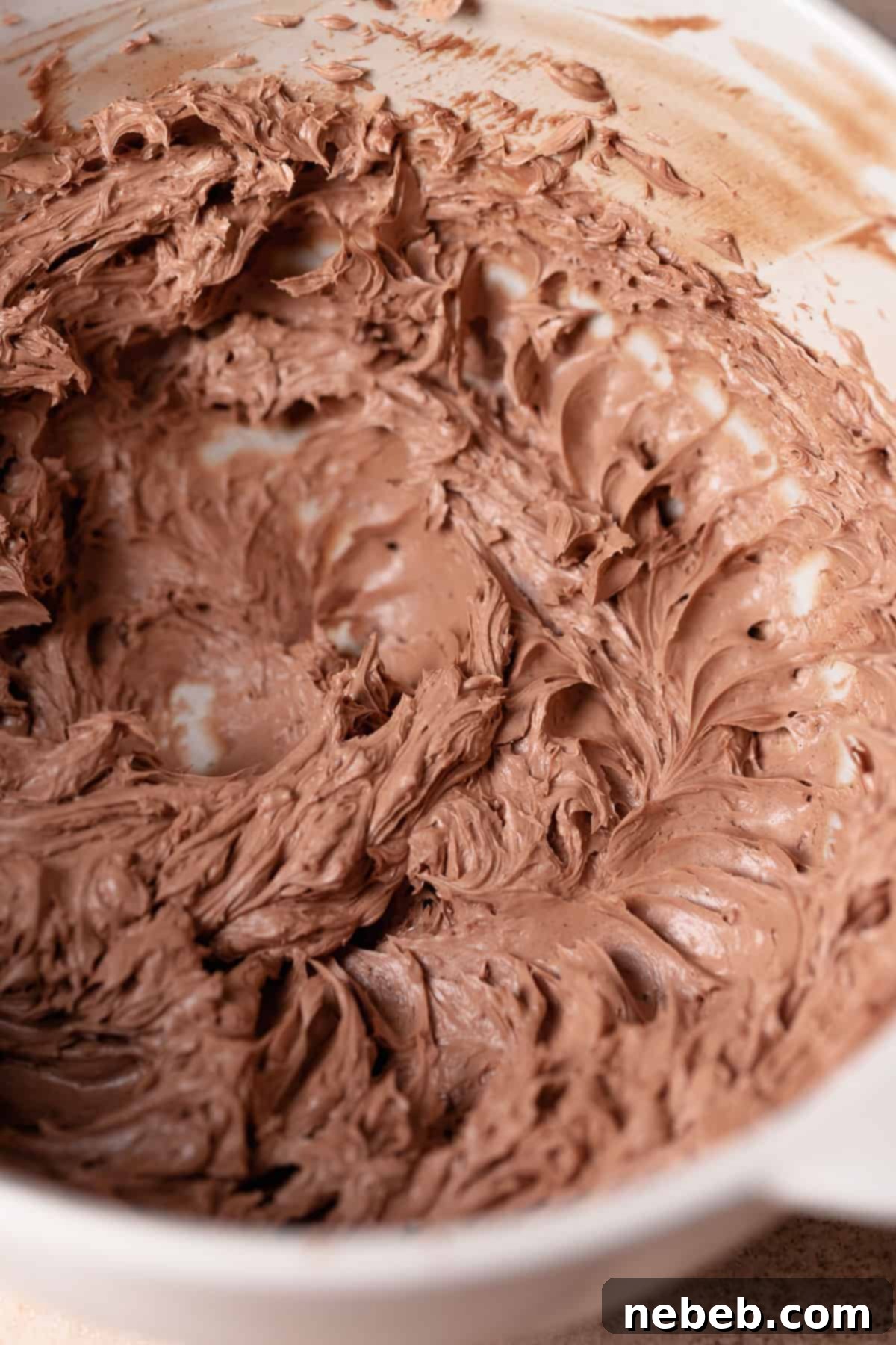 A mixing bowl with milk chocolate buttercream in it.