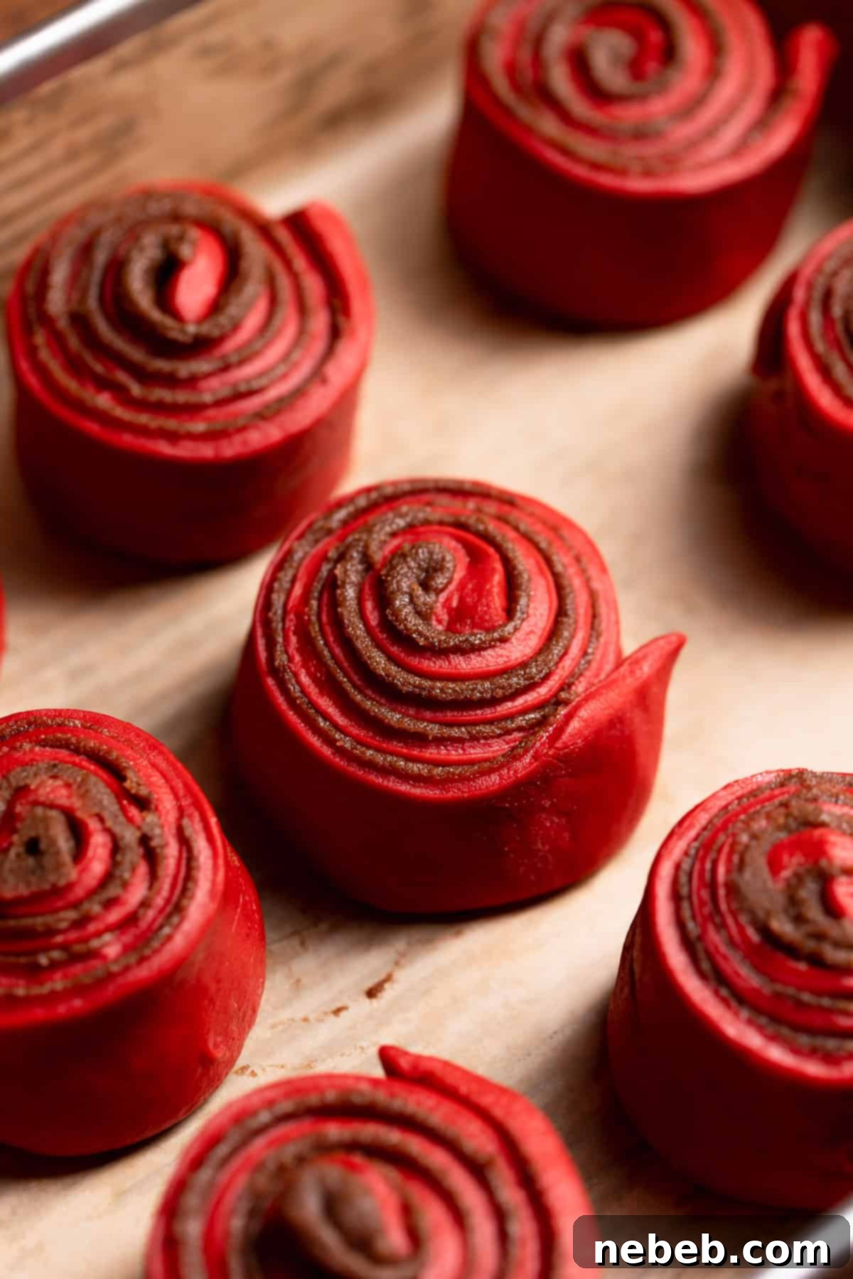 Red cinnamon rolls sitting in a baking pan before rising.