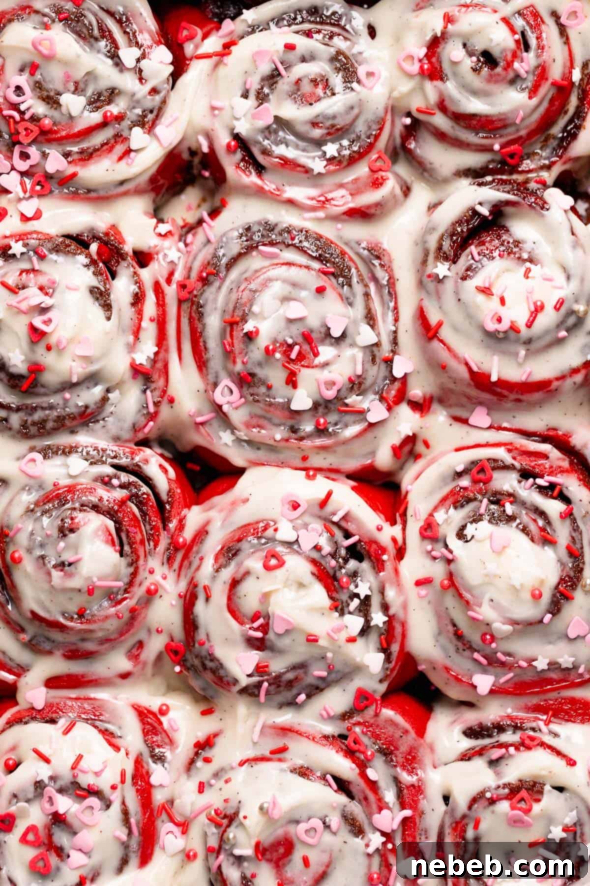 Frosted red velvet rolls with valentine's sprinkles in a baking pan.
