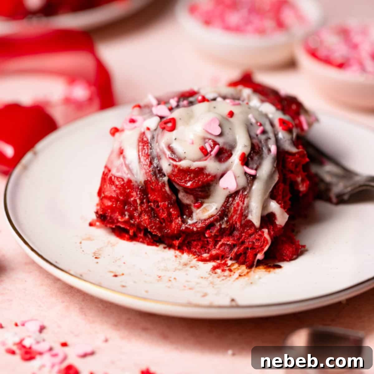 A red velvet bun on a plate with a bite missing to show the gooey texture.