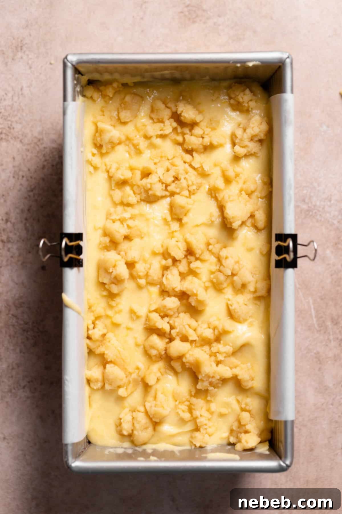 A loaf pan with the lemon cake batter and crumb topping before baking.