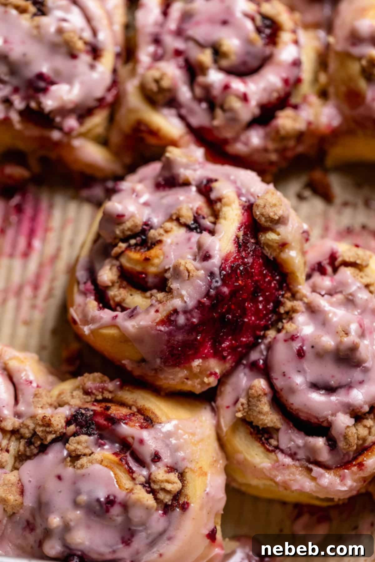 Close-up side view of a baked blackberry raspberry cinnamon roll, showcasing the vibrant swirls of jam and cinnamon sugar within the soft dough.