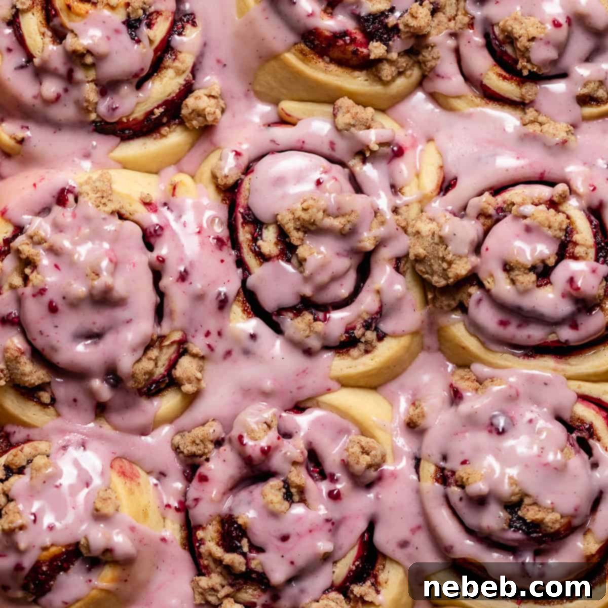 Blackberry rolls with berry icing on top in a baking pan.