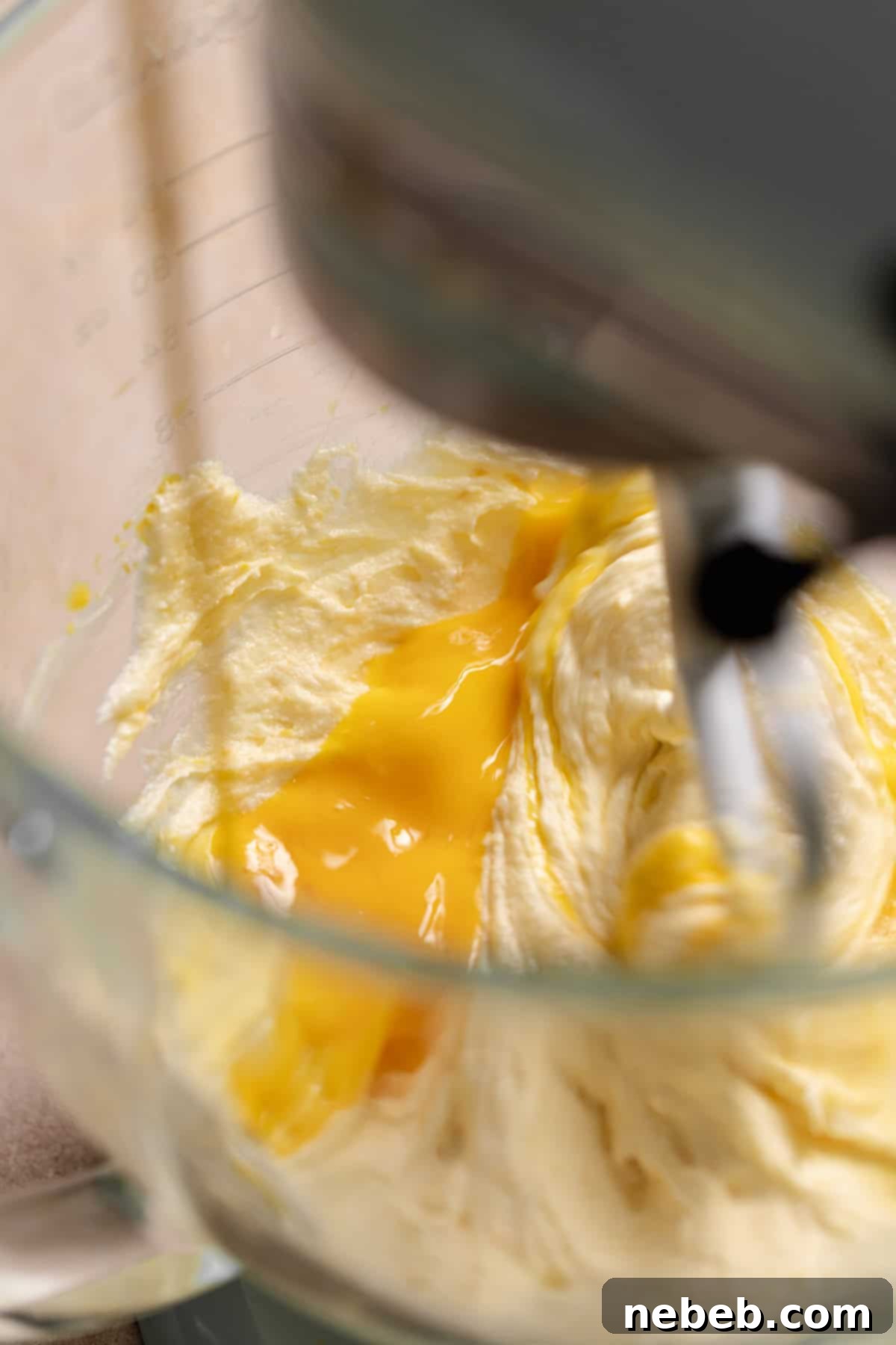 Whisked eggs streaming into a mixing bowl.