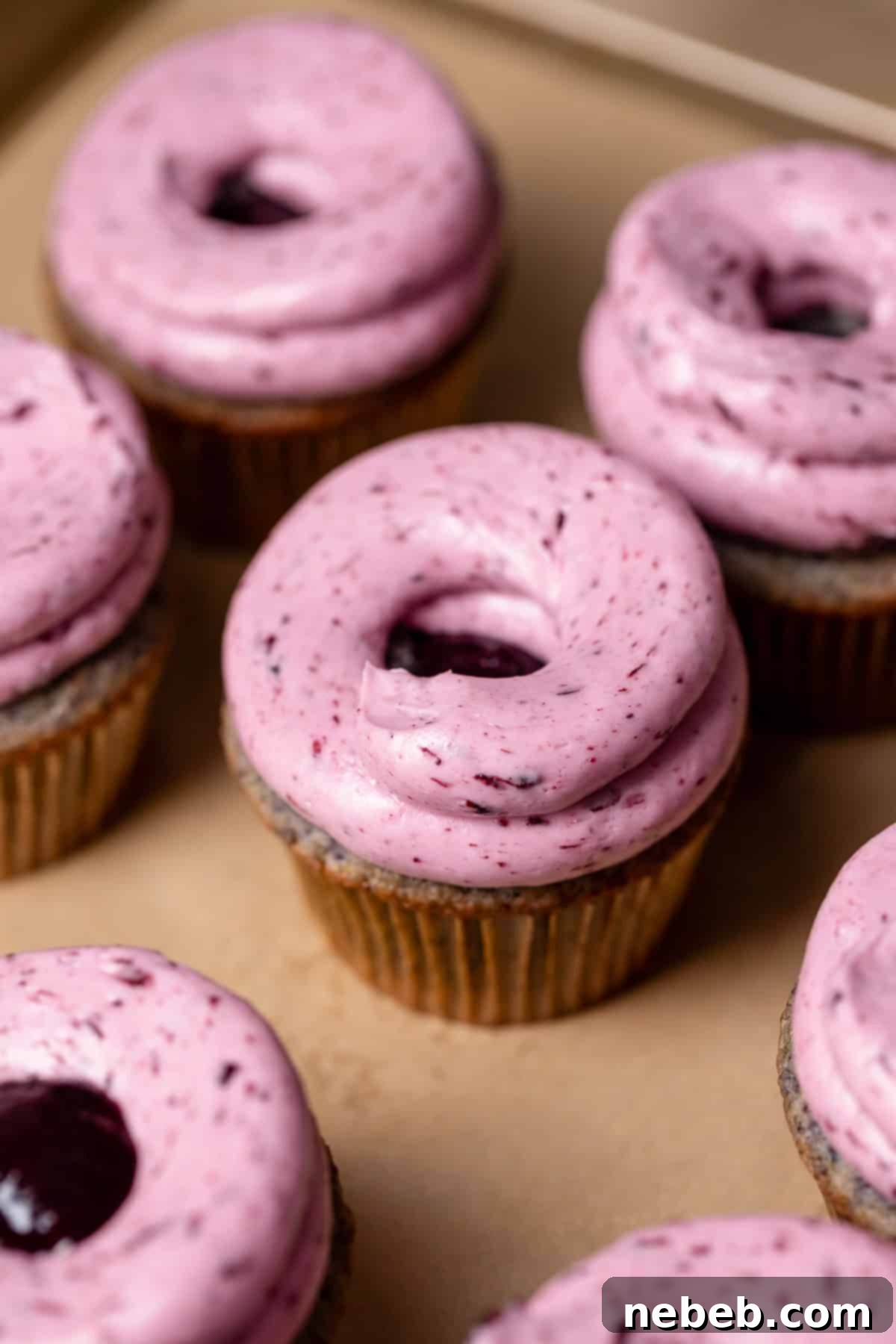 Cupcakes on a baking tray with frosting swirled on top.