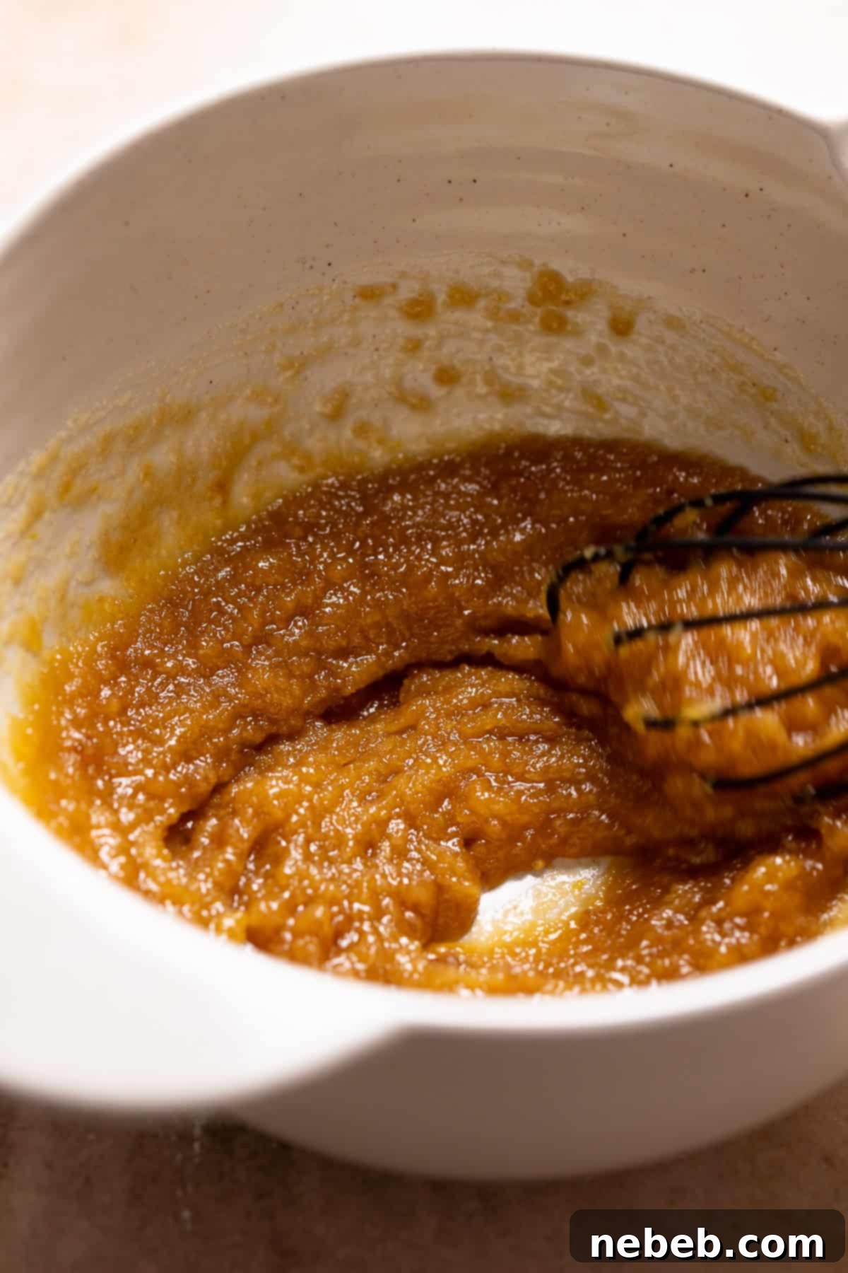 A whisk mixing the butter and sugars together.