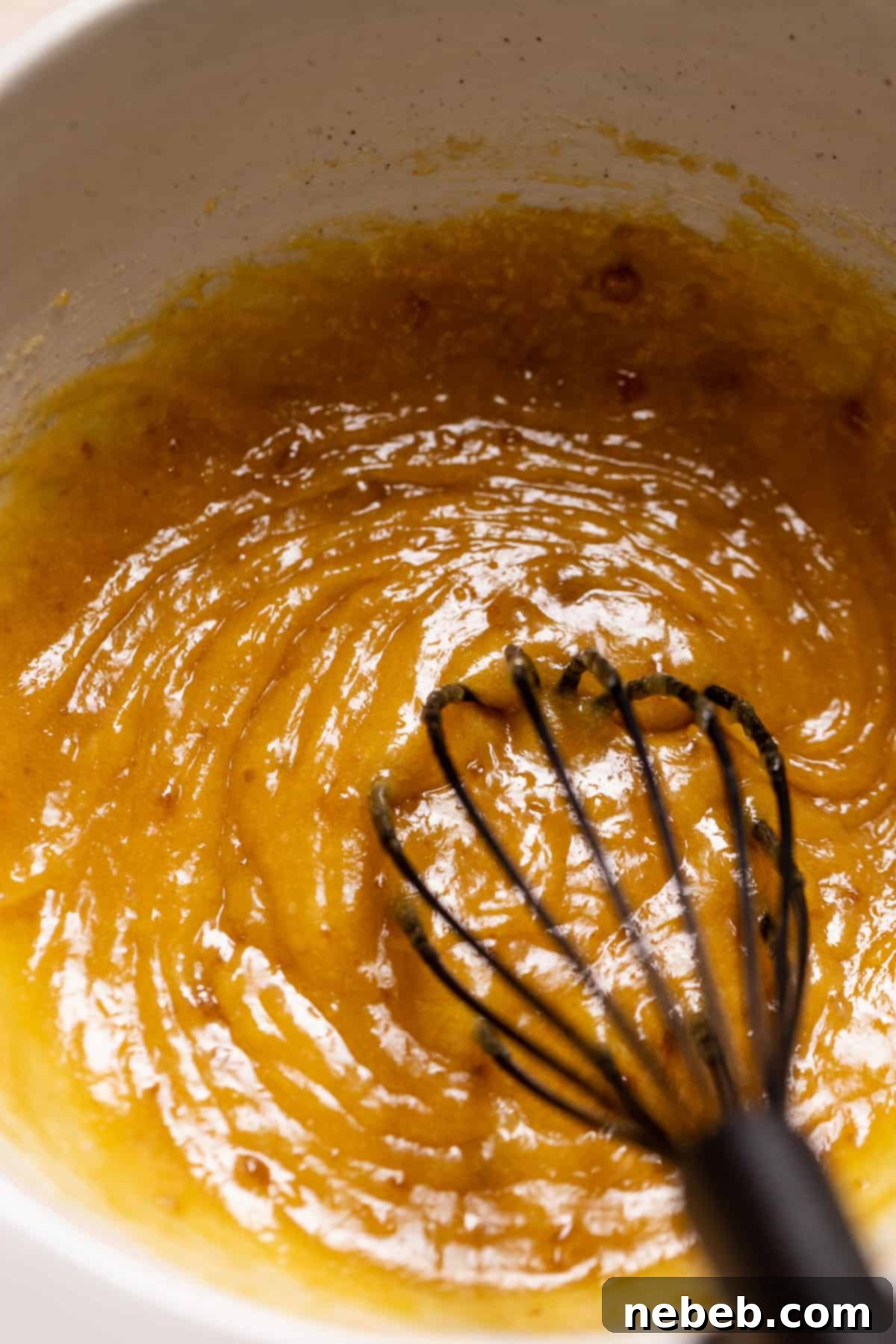 A whisk mixing the eggs and lemon juice into the cookie dough.