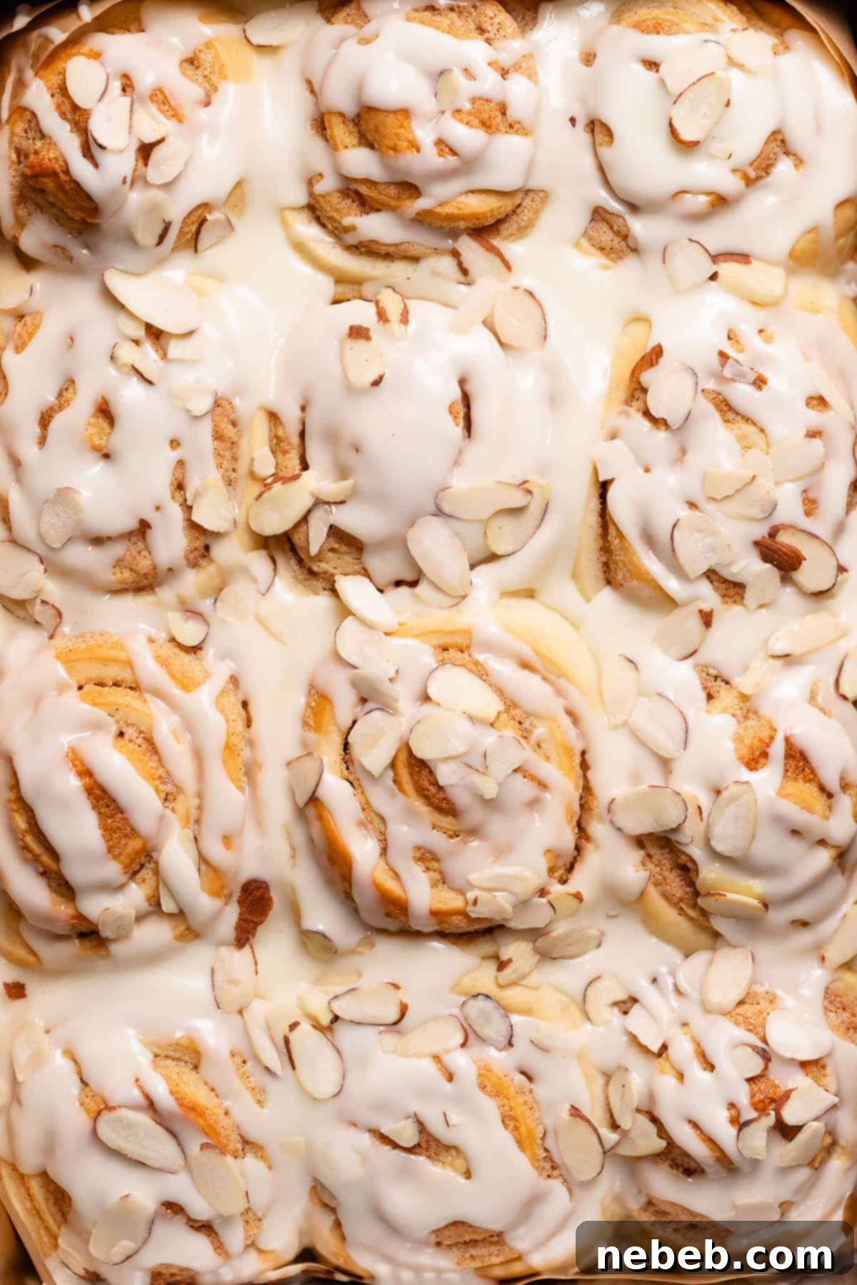 Almond rolls with almond glaze and sliced almonds in the baking pan.