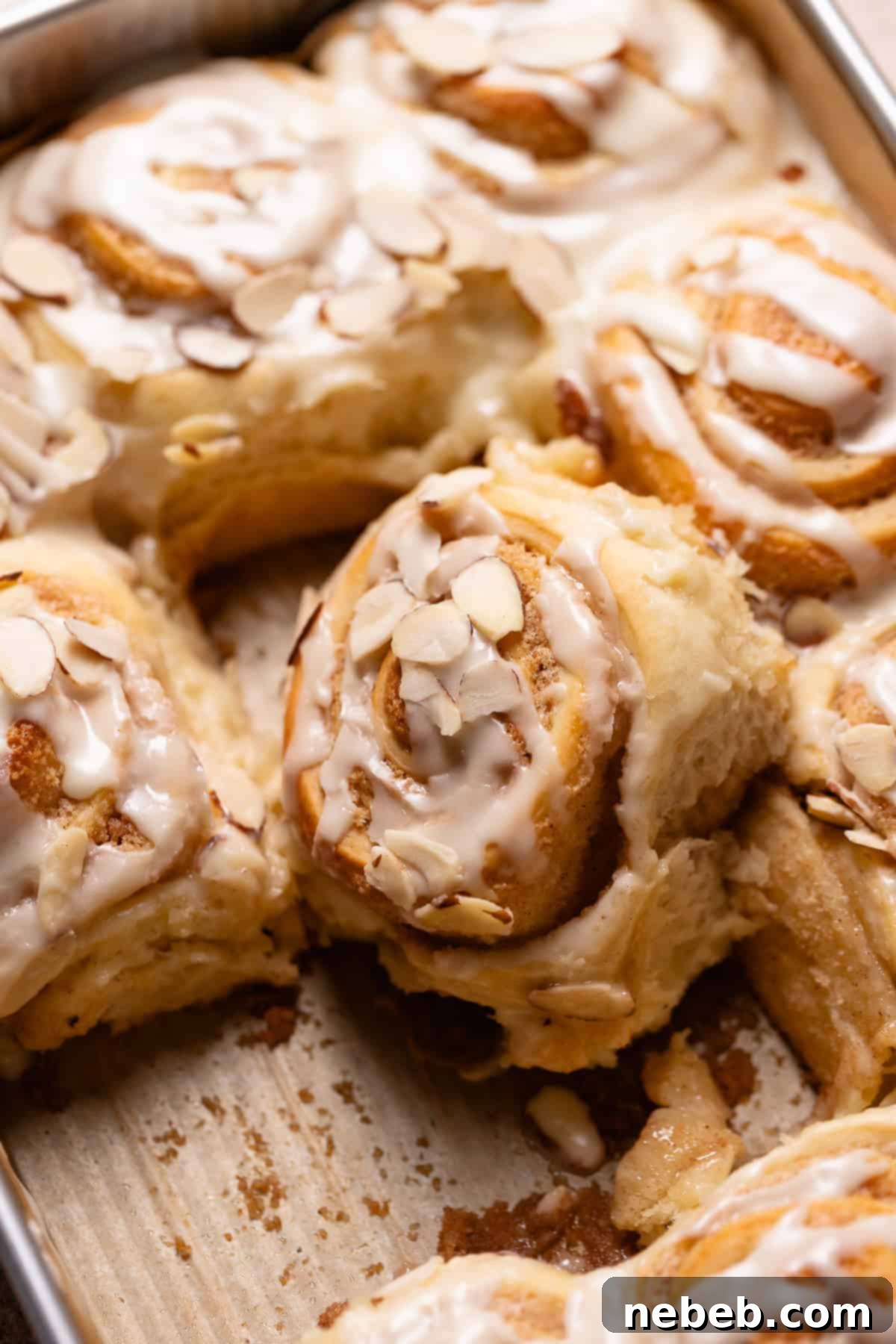 An almond roll on its side in the baking pan to show the soft and gooey texture.