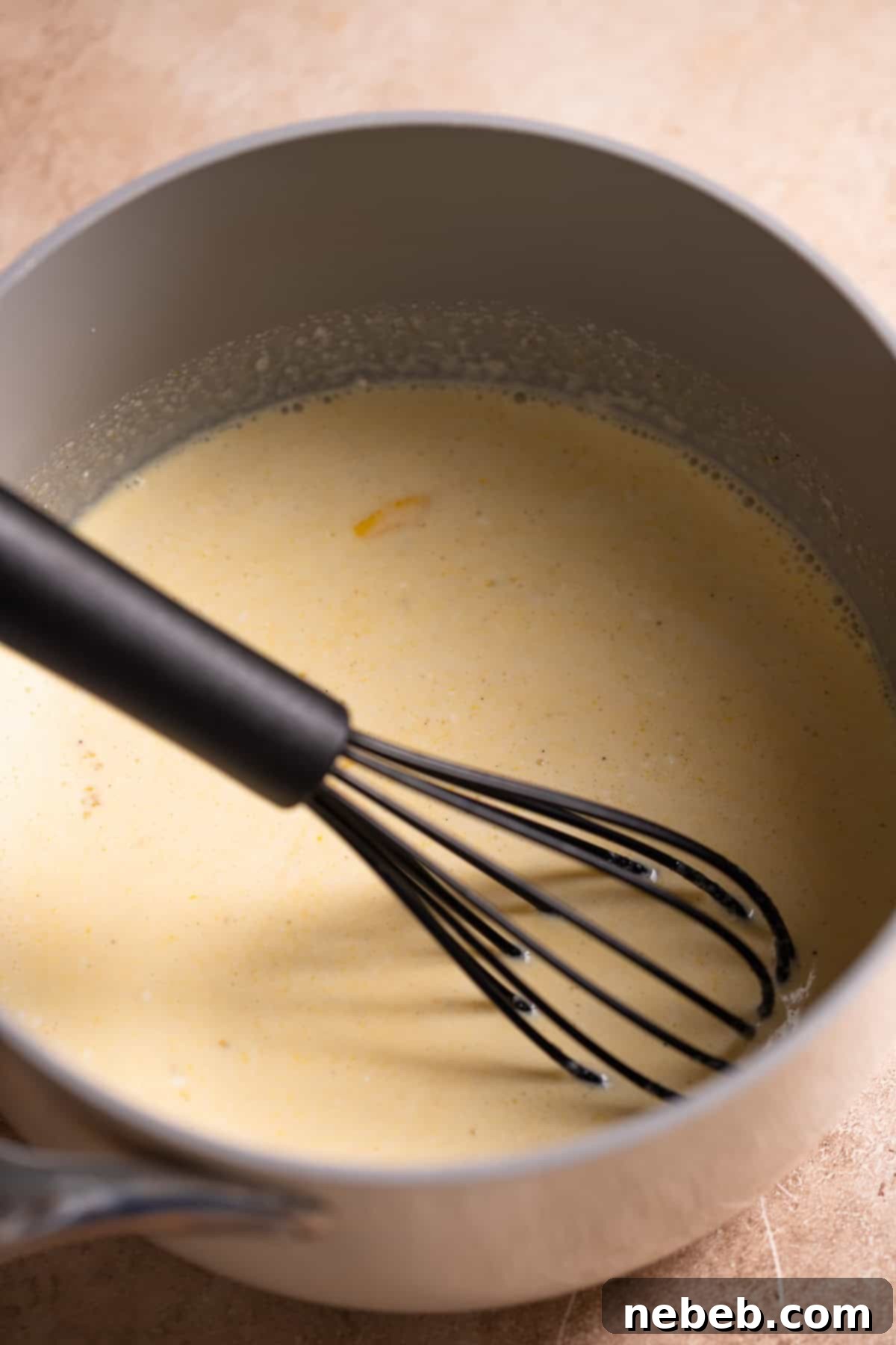 Heavy cream, egg yolks, and sugar being gently cooked in a saucepan, forming the base for the chocolate mousse.
