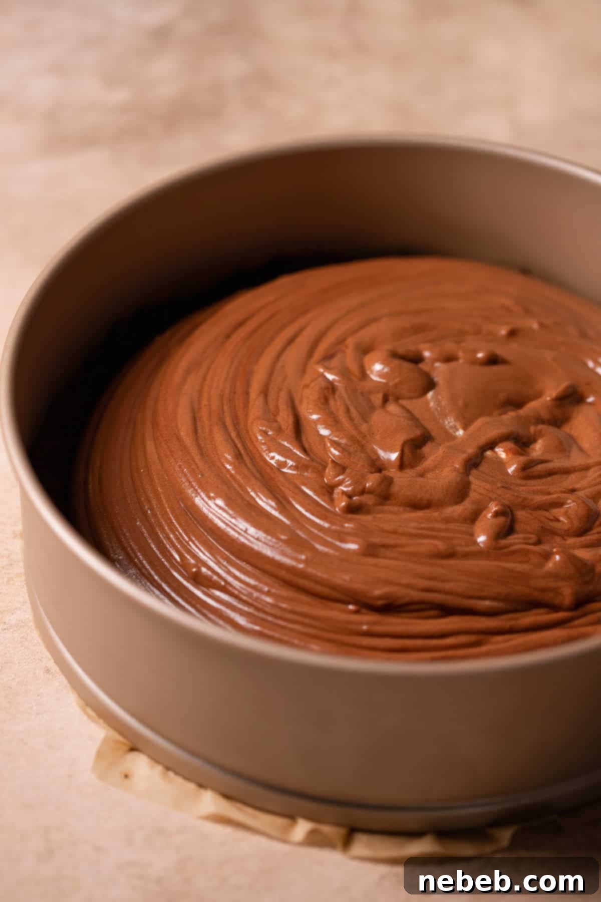 Silky chocolate mousse filling being poured smoothly over the pre-baked Oreo crust in a springform pan.