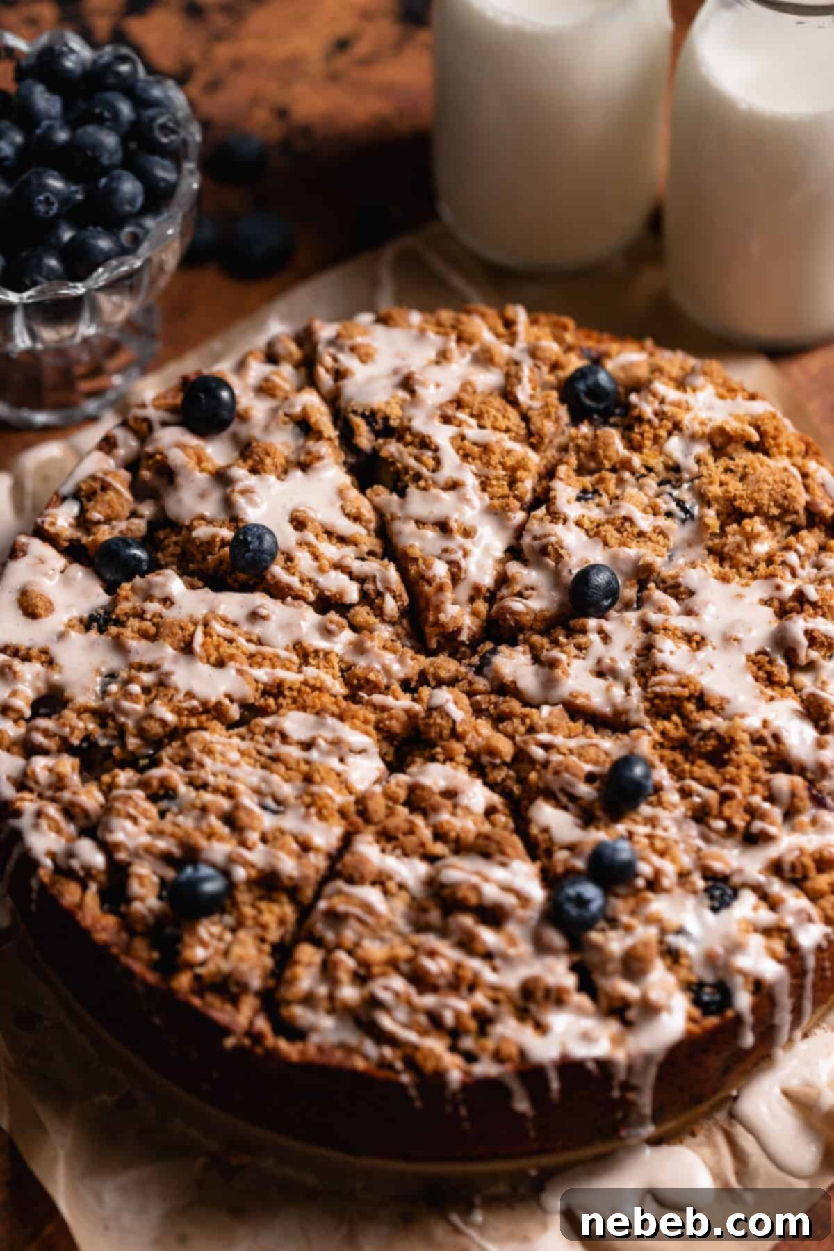 Luscious Blueberry Sour Cream Coffee Cake 11 Blueberry coffee cake with vanilla glaze on brown parchment paper.