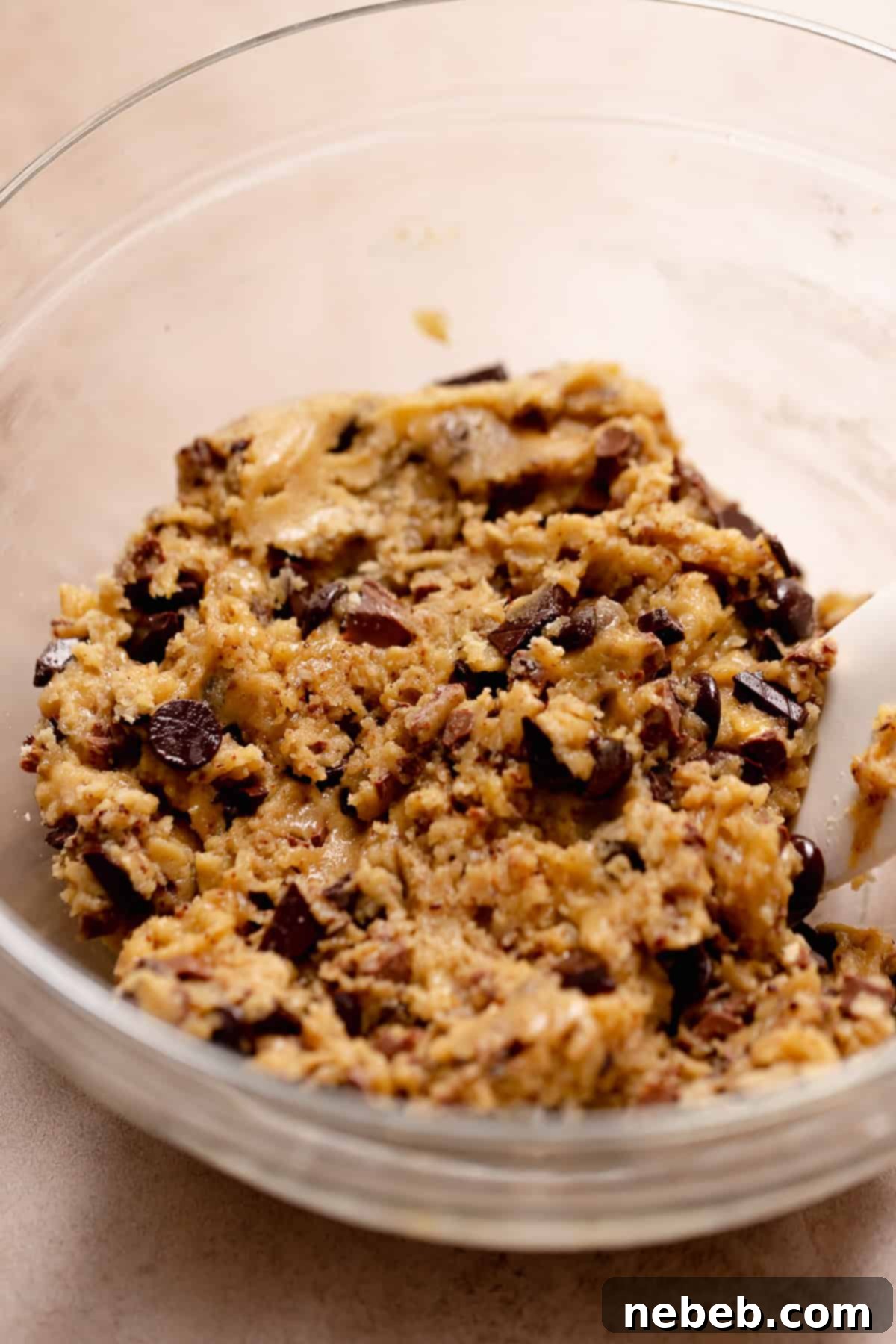 A glass bowl with the brown butter chocolate chip cookie dough in it.