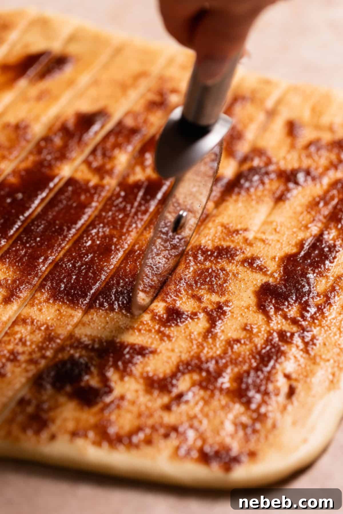 A pizza wheel cutting strips of the cinnamon sugar dough.
