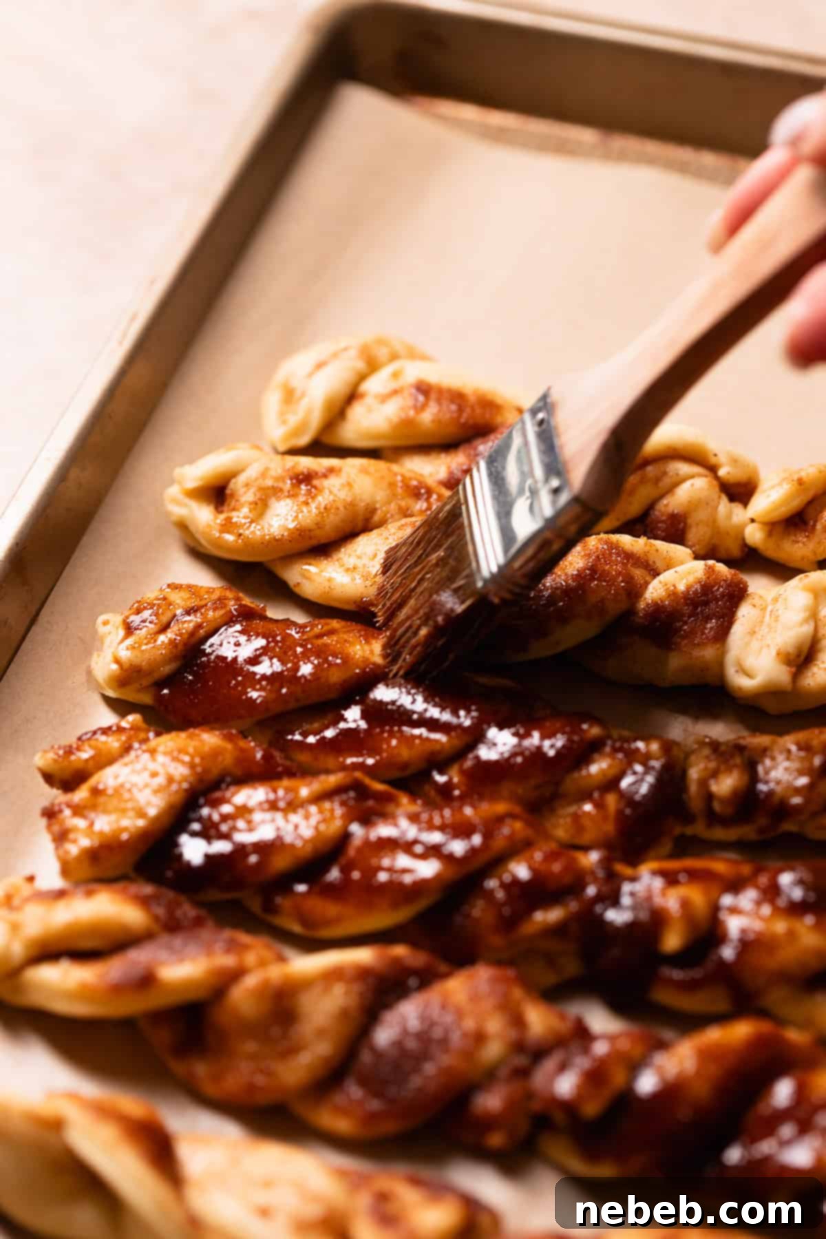 Cinnamon twists being brushed with cinnamon sugar.