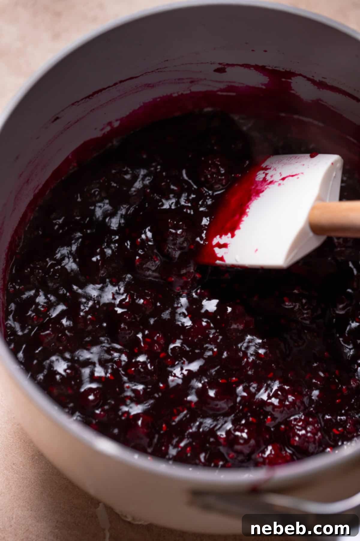 The mixed berry jam filling simmering in a pot, showing chunks of berries.