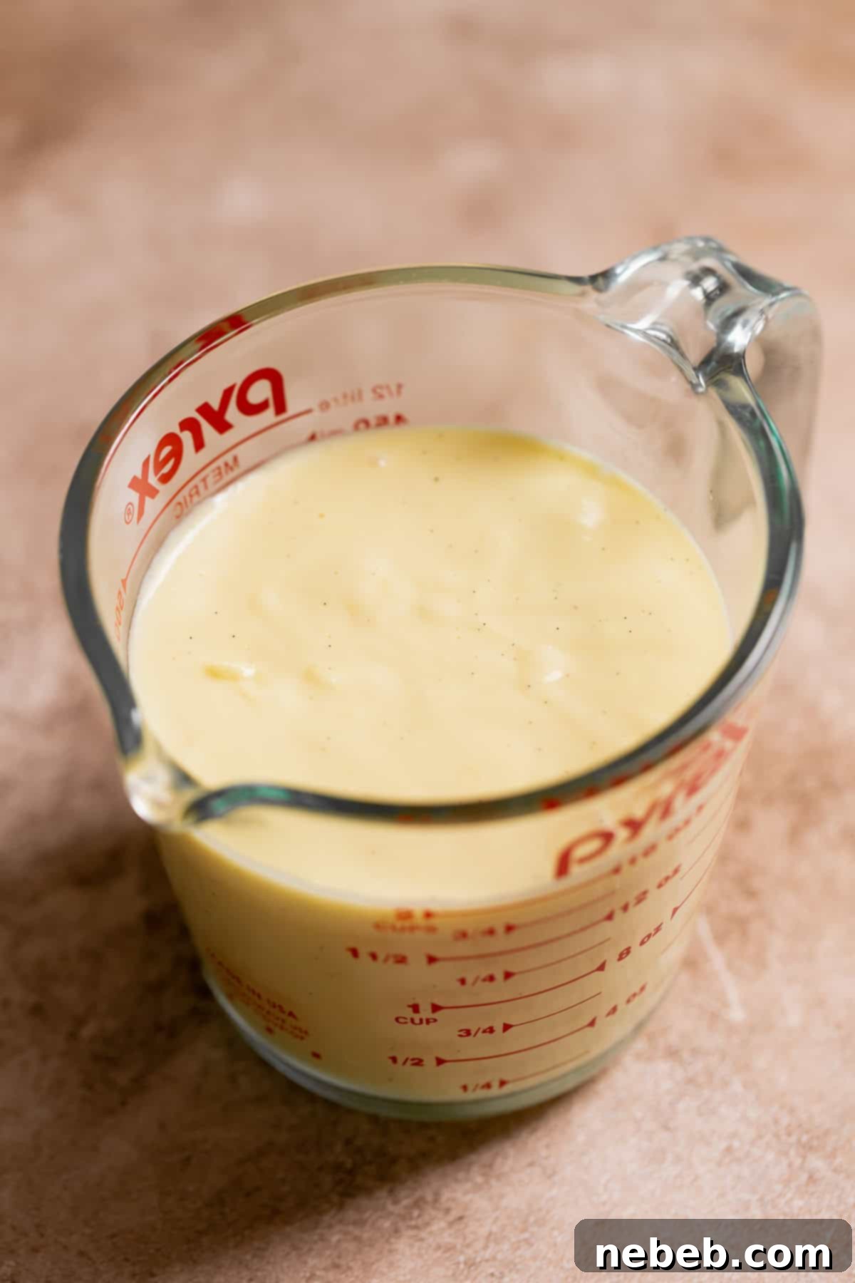 Decadent Banana Pudding Cinnamon Rolls 12 A glass measuring cup full of smooth homemade vanilla pudding.