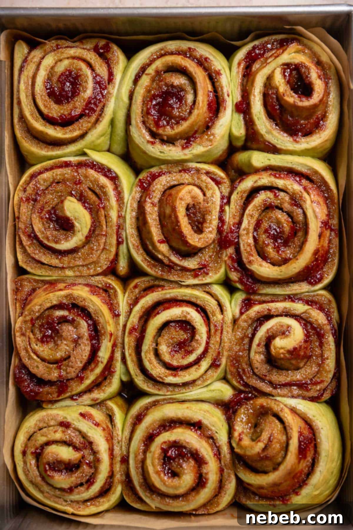 Freshly baked matcha cinnamon rolls in a metal baking pan, golden brown.