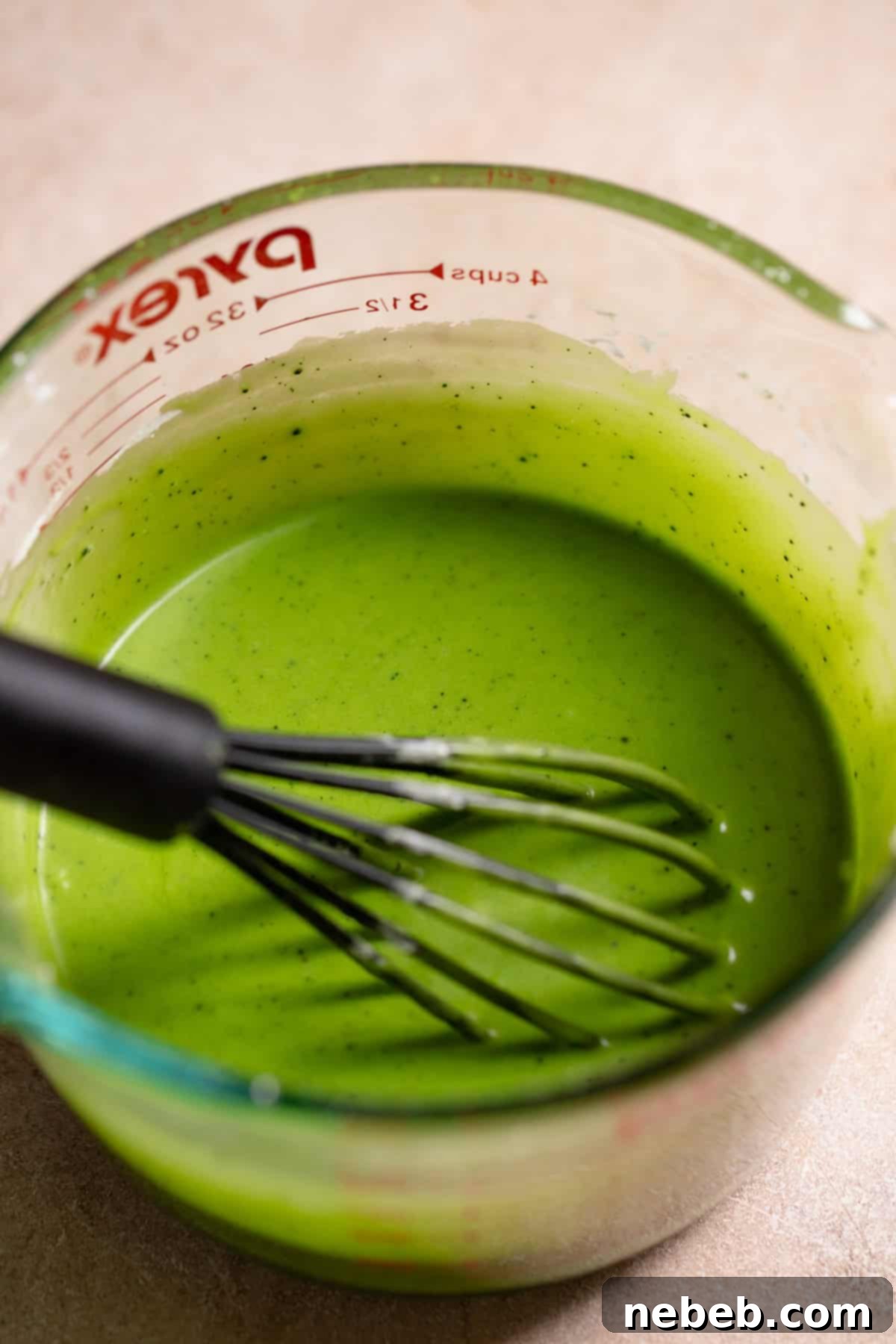 Smooth, vibrant green matcha icing in a glass bowl with a whisk, ready for drizzling.