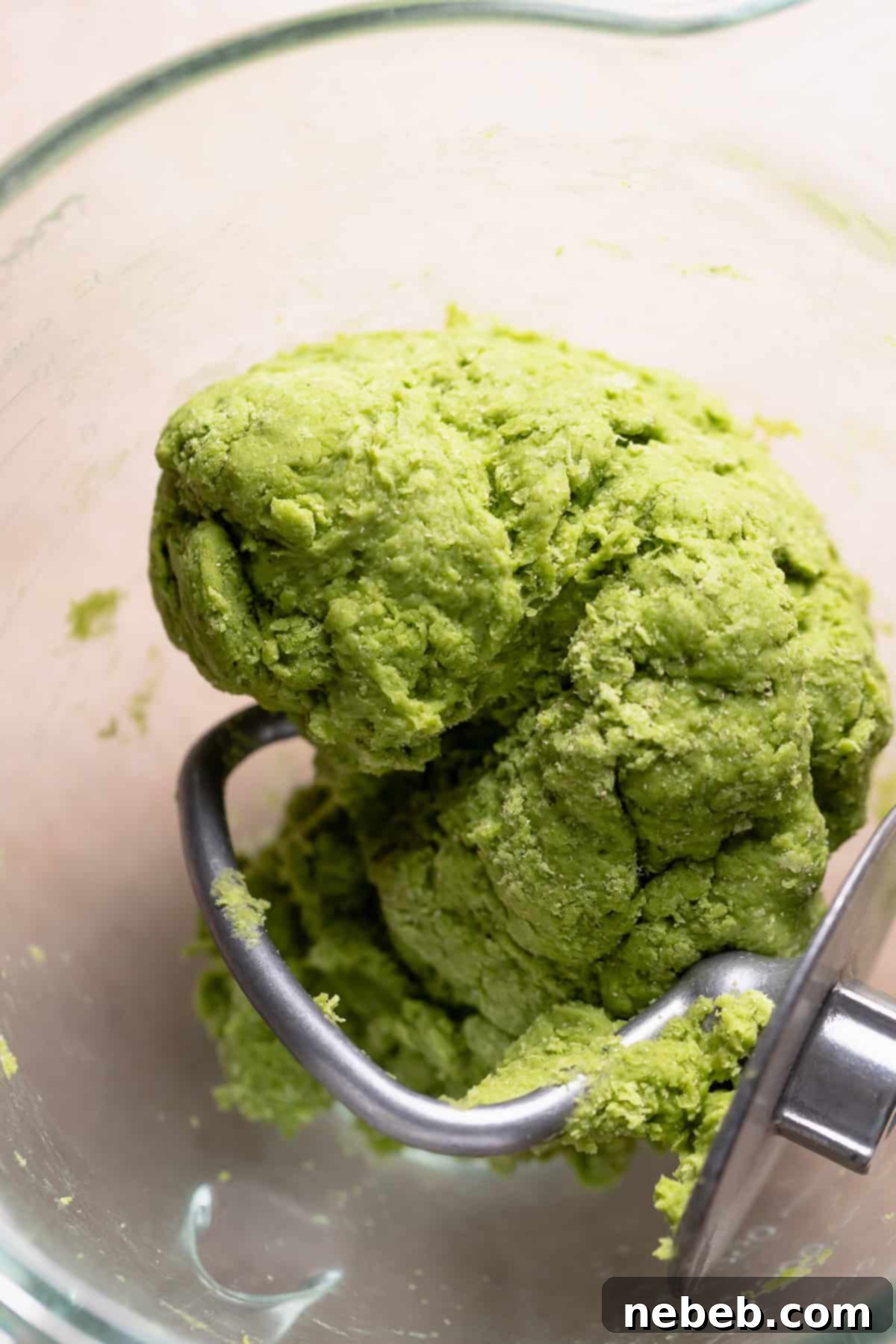 Matcha dough ball in a stand mixer bowl, looking shaggy before butter is added.