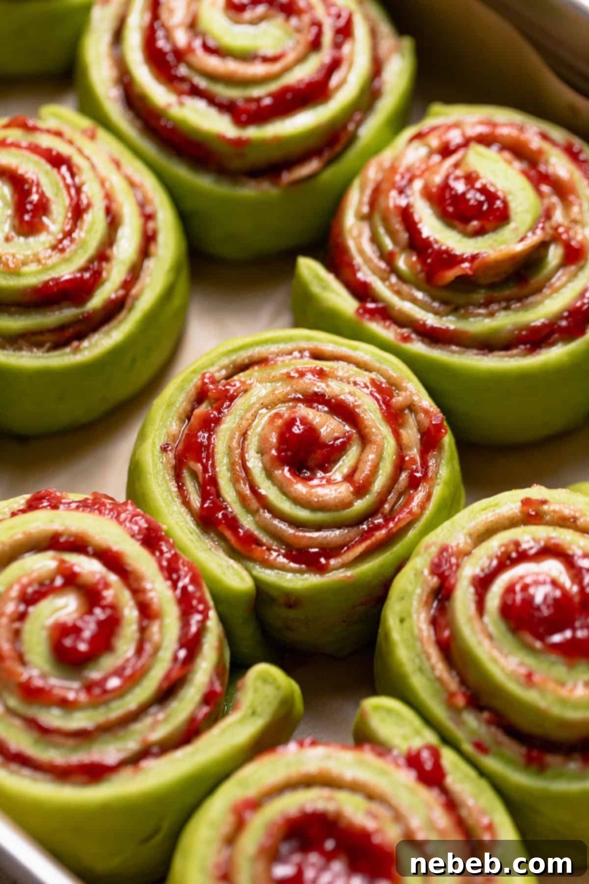 Matcha cinnamon rolls, doubled in size and pillowy, ready for baking in a pan.