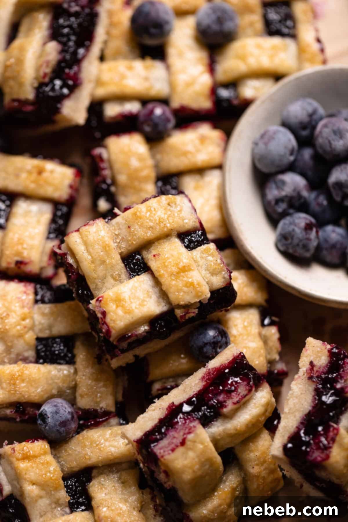 Blueberry pie bars with lattice tops in a pile, perfectly golden brown.