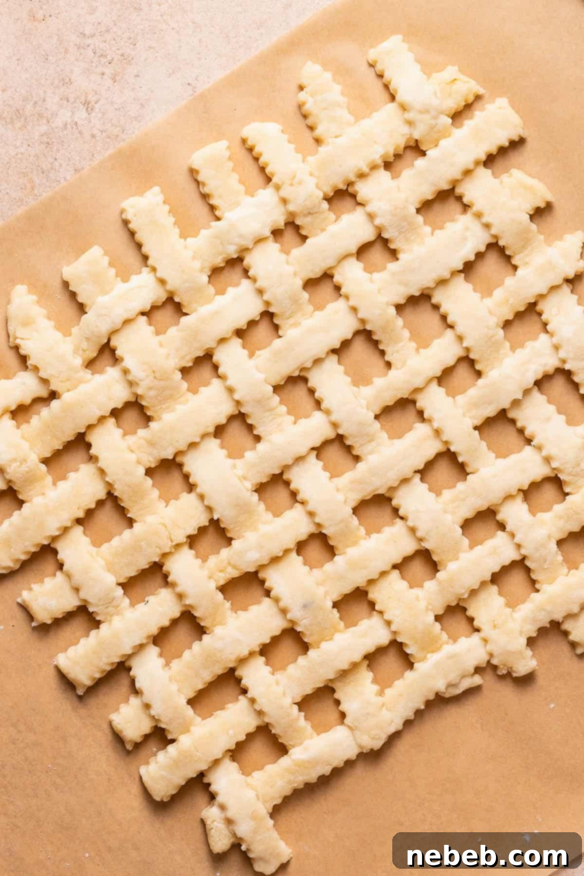 Pie crust strips arranged into a lattice top on parchment paper, ready to be frozen.
