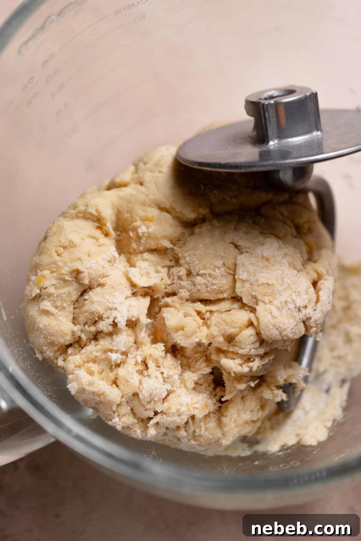 A rough, dry dough ball in a mixer bowl.
