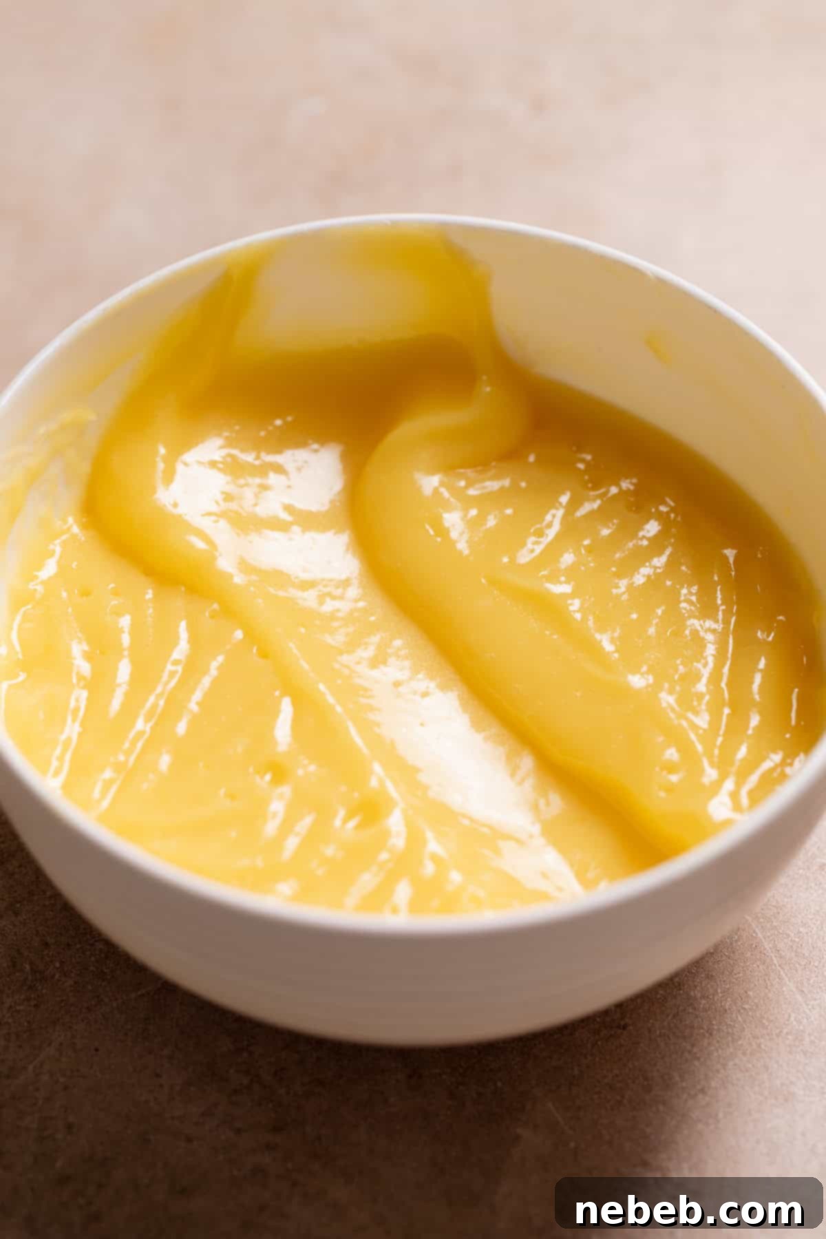 Fresh orange curd in a white bowl with some of it scooped out to show the texture.