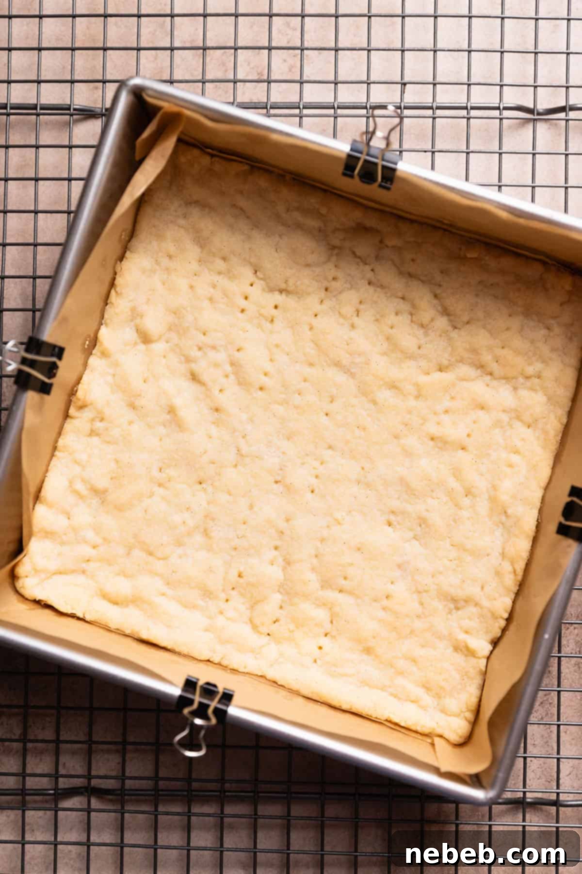 A pan with the golden baked shortbread crust cooling on a wire rack, ready for the filling.