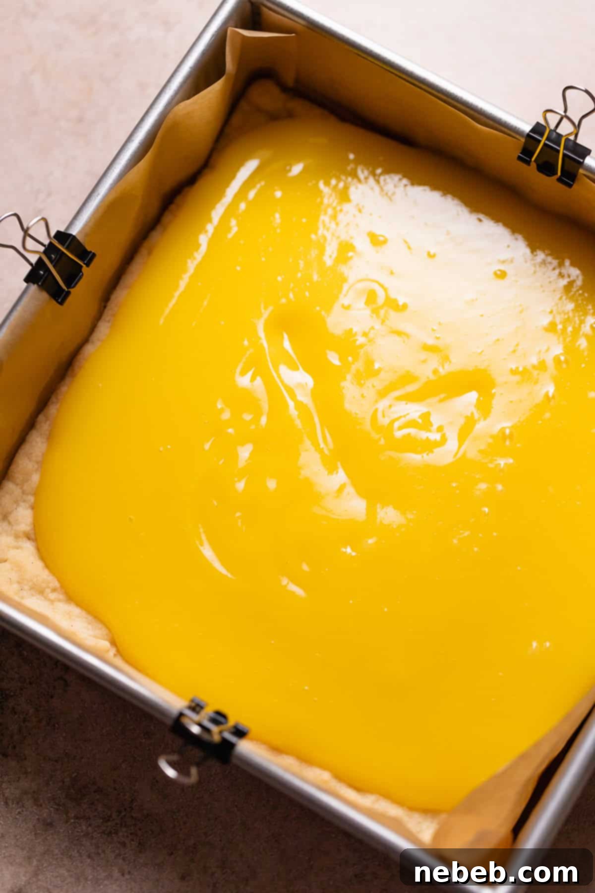 Lemon curd being spread evenly over the top of the perfectly baked shortbread crust.