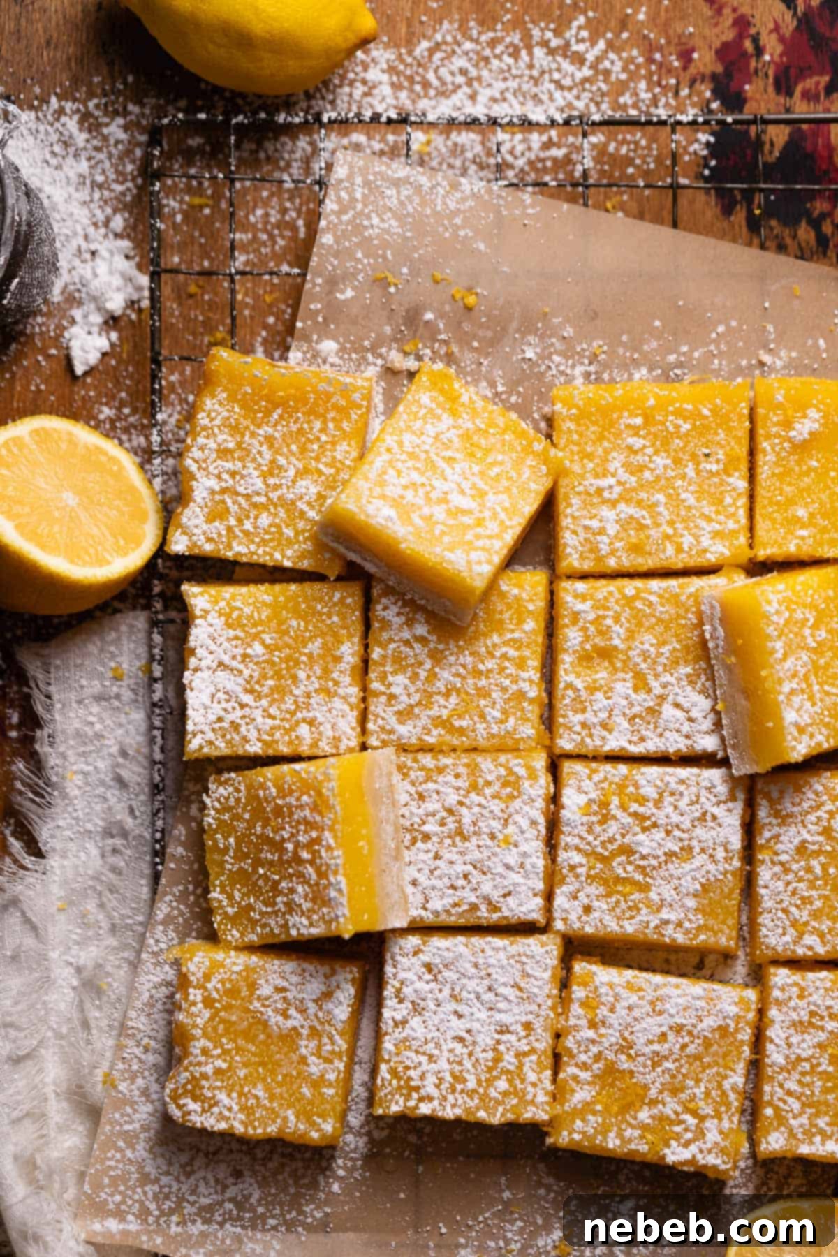 Beautifully arranged lemon bars, cut into neat squares and dusted with powdered sugar, resting on brown parchment paper.